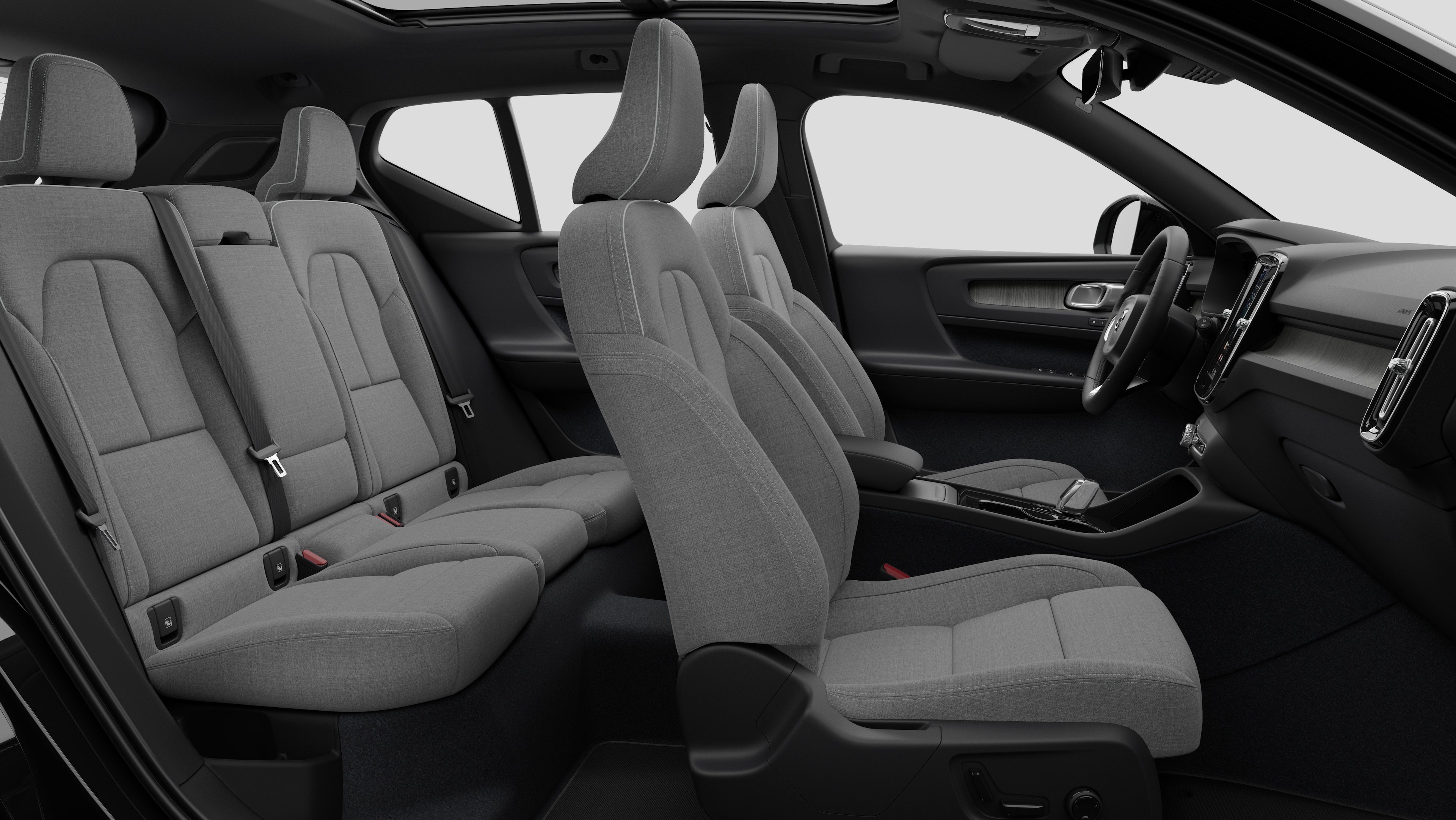 Vista lateral do interior do carro Volvo mostrando os bancos dianteiros, traseiros do passageiro, volante, painel de instrumentos e console central, contra um plano de fundo de estúdio simples.