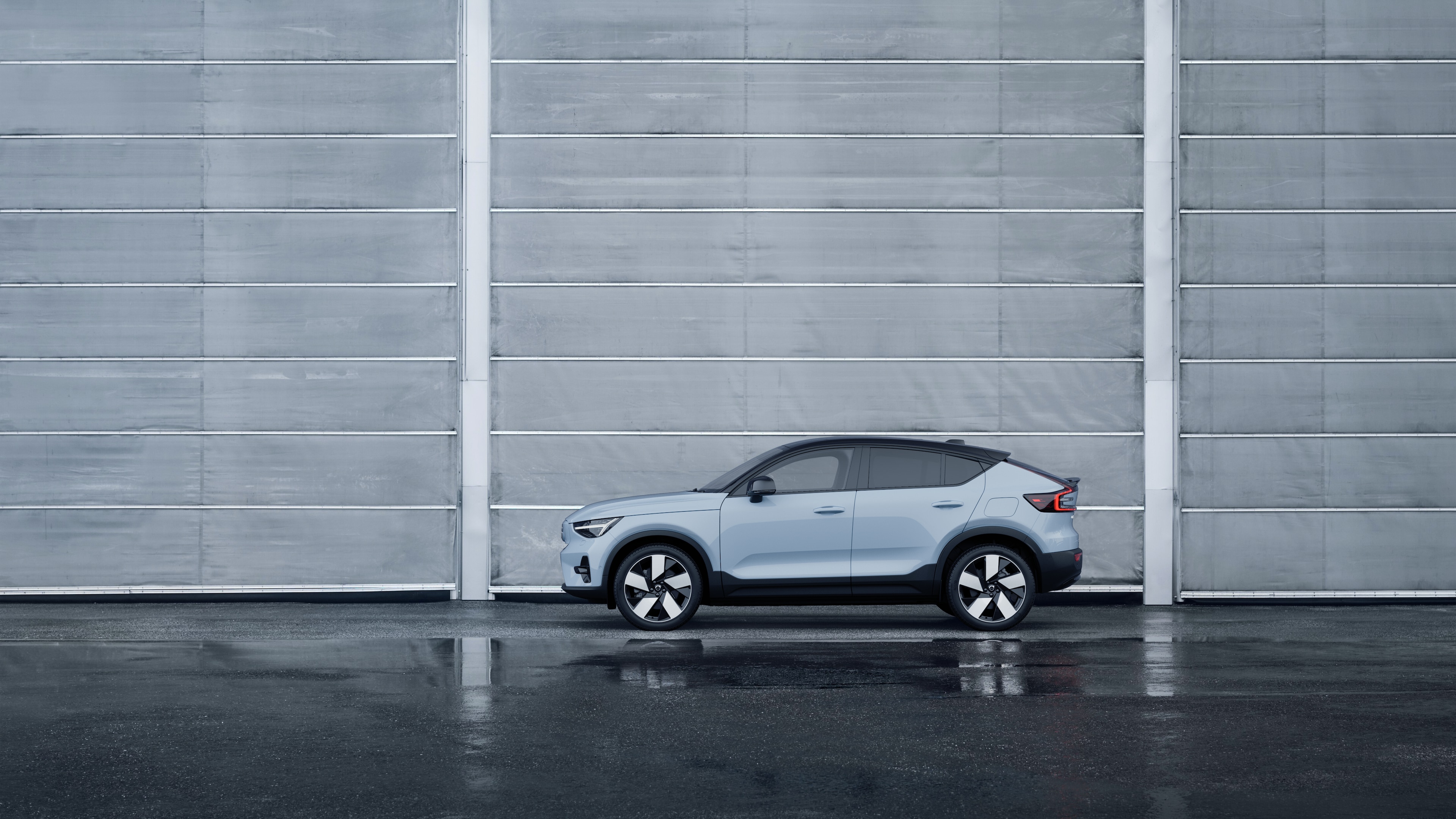 Volvo car, side view, parked against a plain concrete wall background.