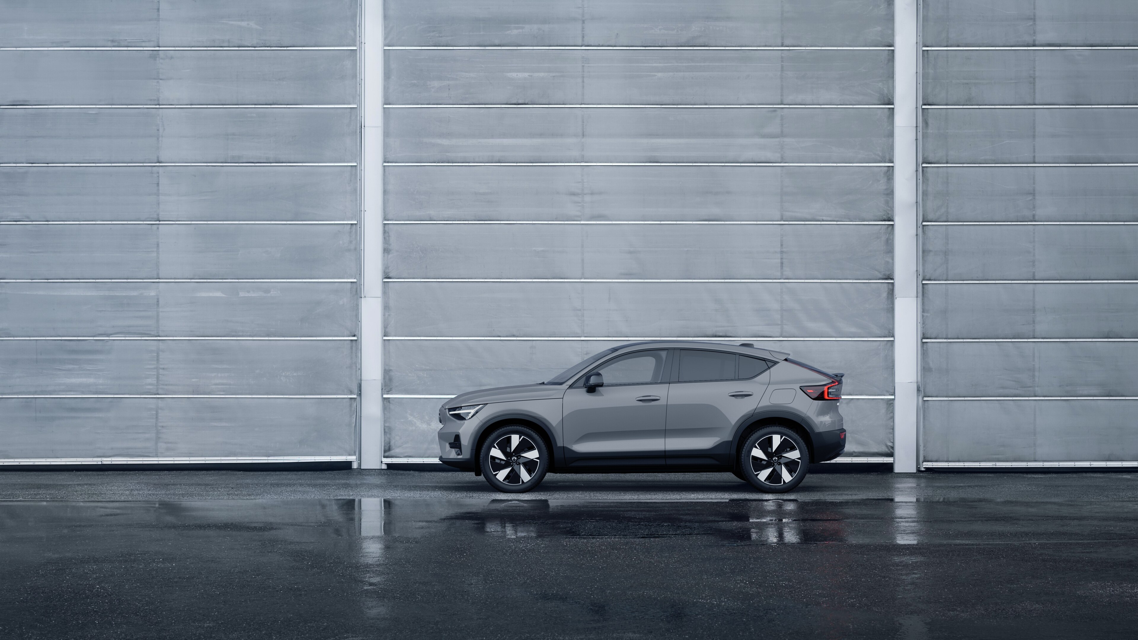 Volvo, zijaanzicht, geparkeerd tegen een effen betonnen muurachtergrond.