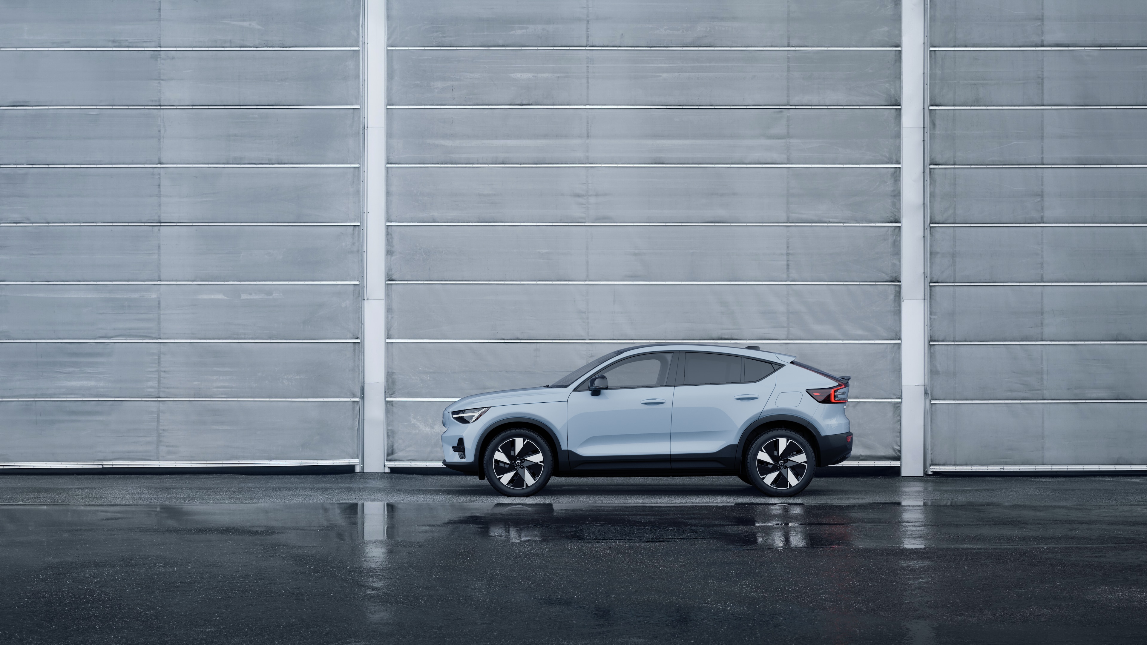 Volvo car, side view, parked against a plain concrete wall background.