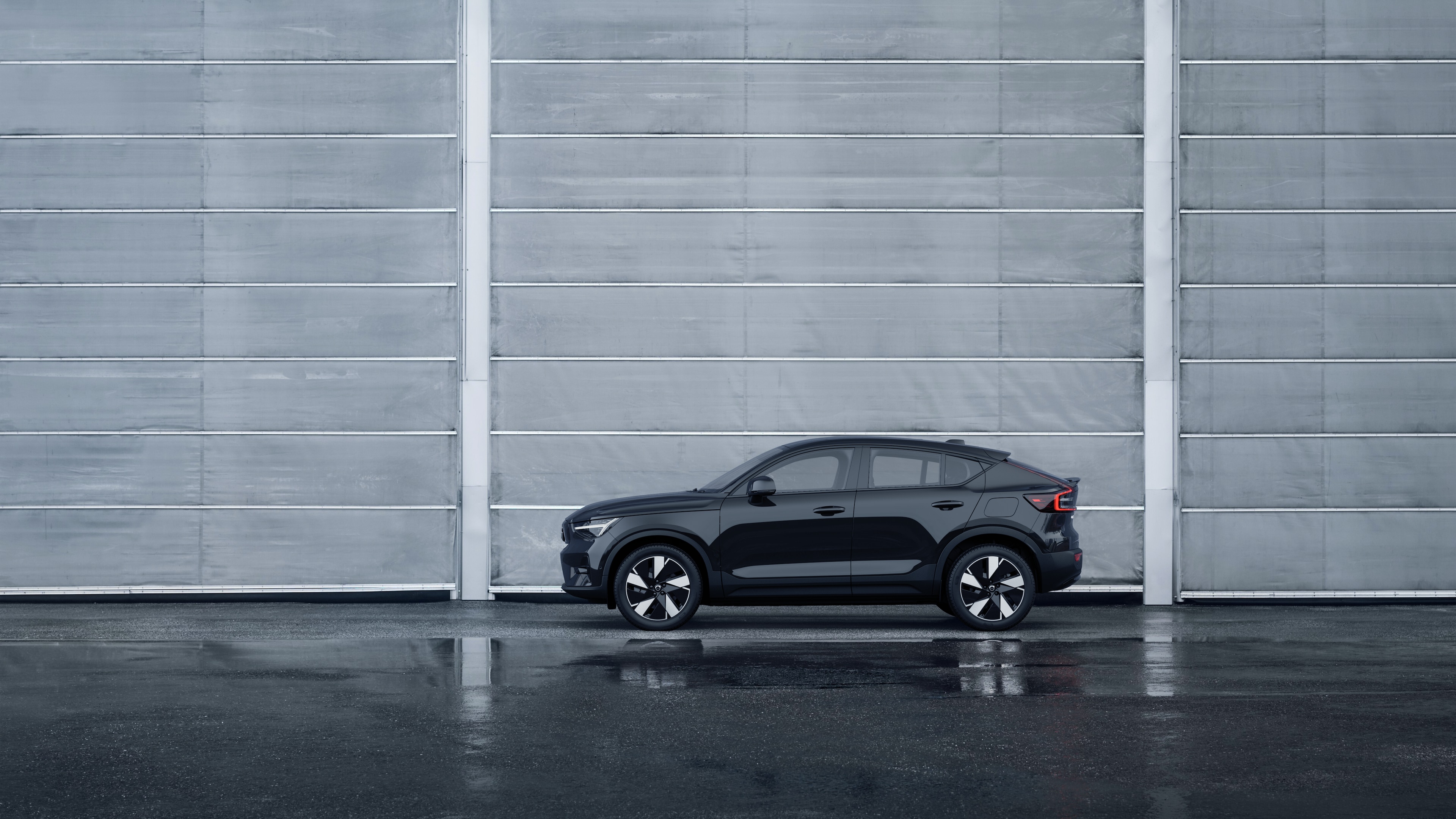 Volvo car, side view, parked against a plain concrete wall background.