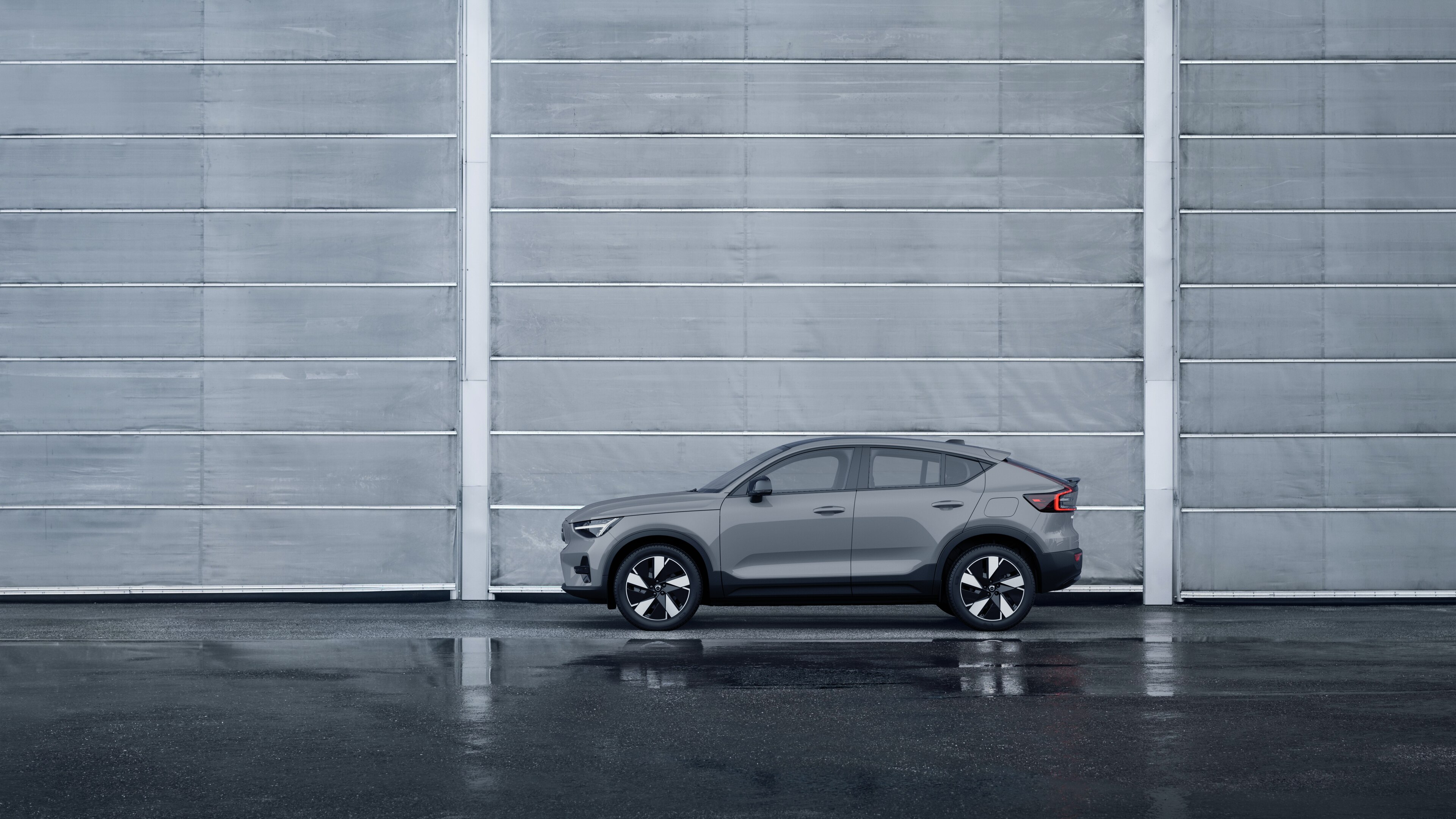 Volvo, zijaanzicht, geparkeerd tegen een effen betonnen muurachtergrond.