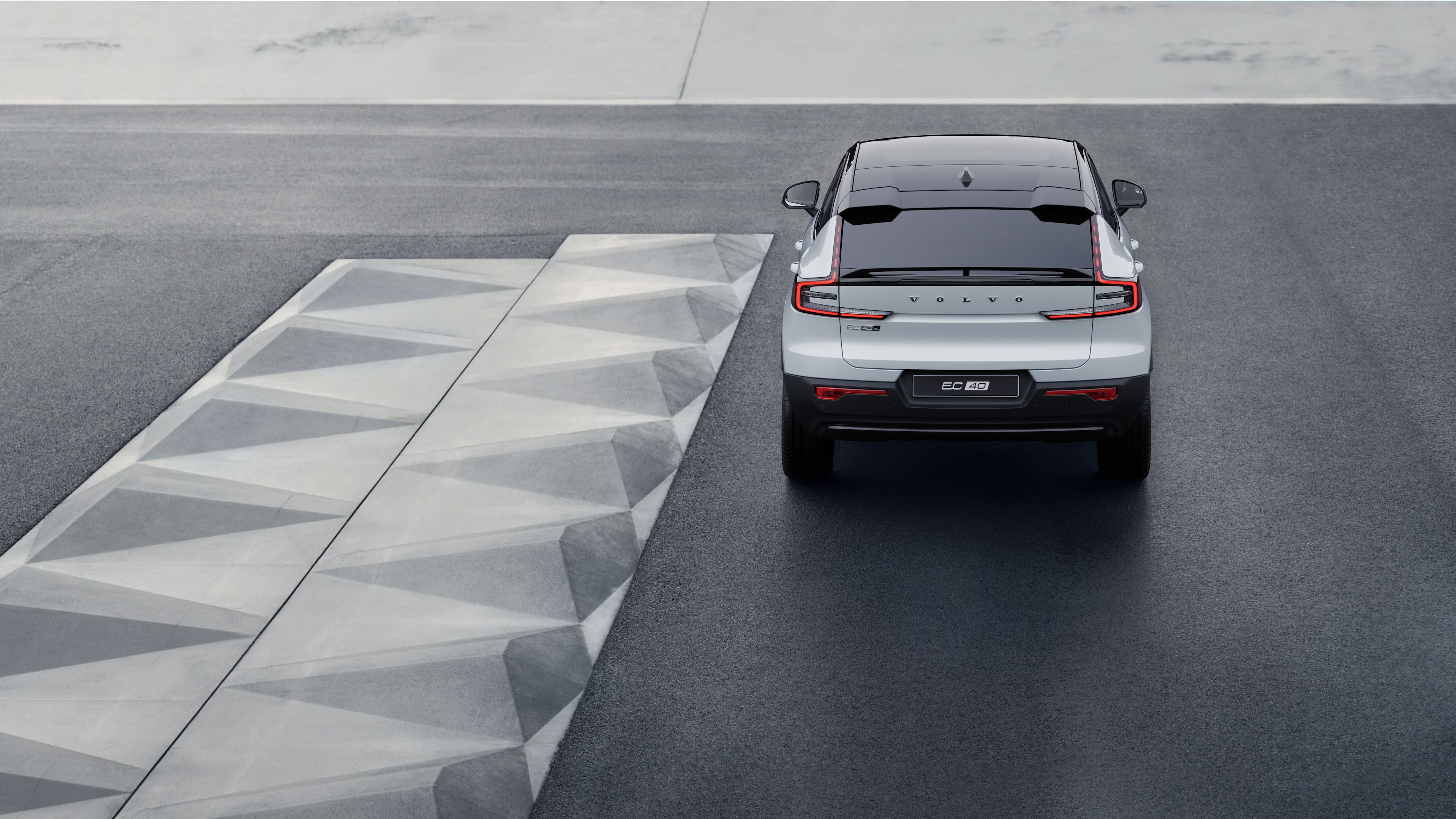 Vue arrière d’une voiture Volvo sur une route côtière sinueuse avec un arrière-plan en bord de mer.