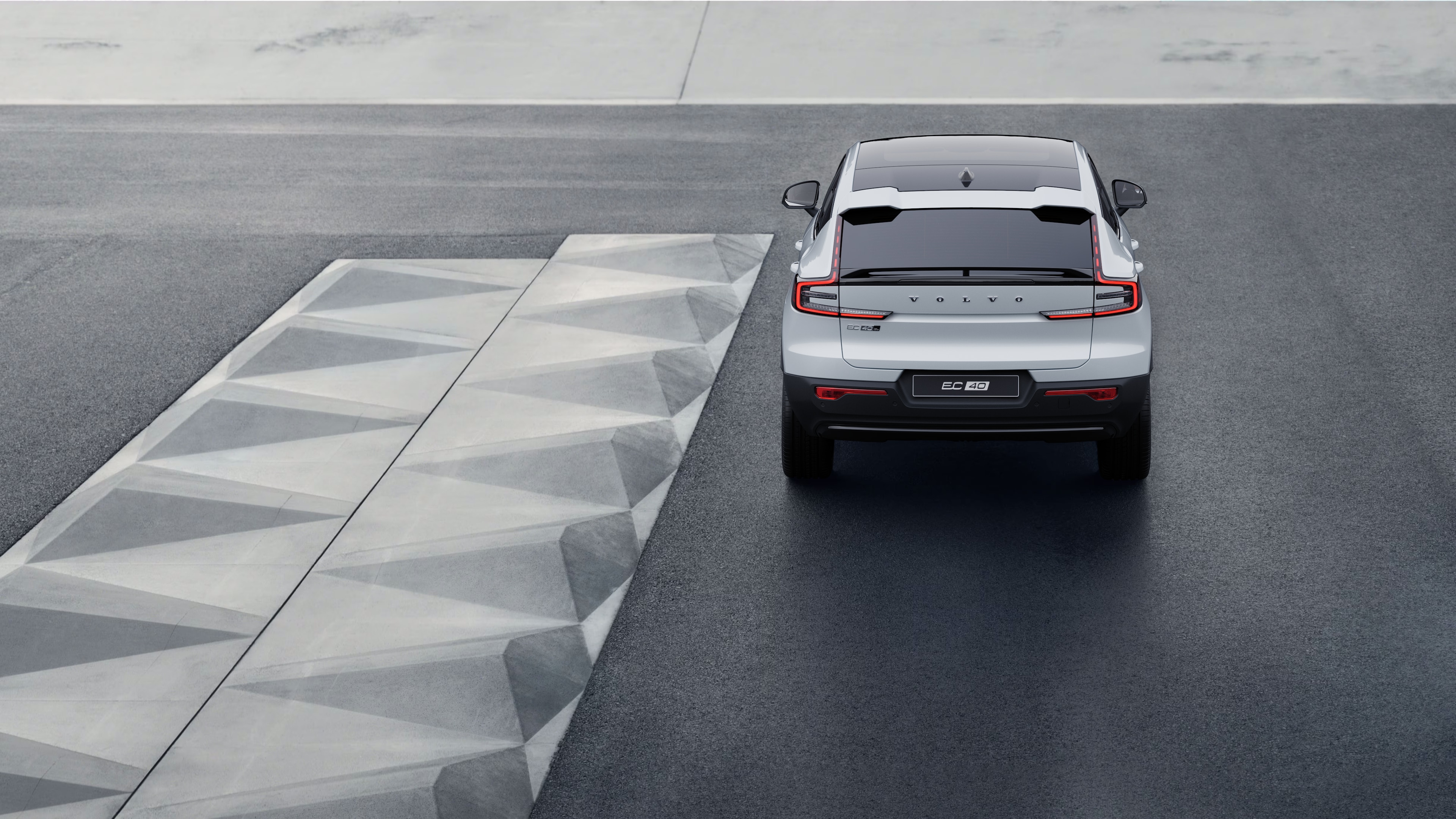 Vue arrière d’une voiture Volvo sur une route côtière sinueuse avec un arrière-plan en bord de mer.