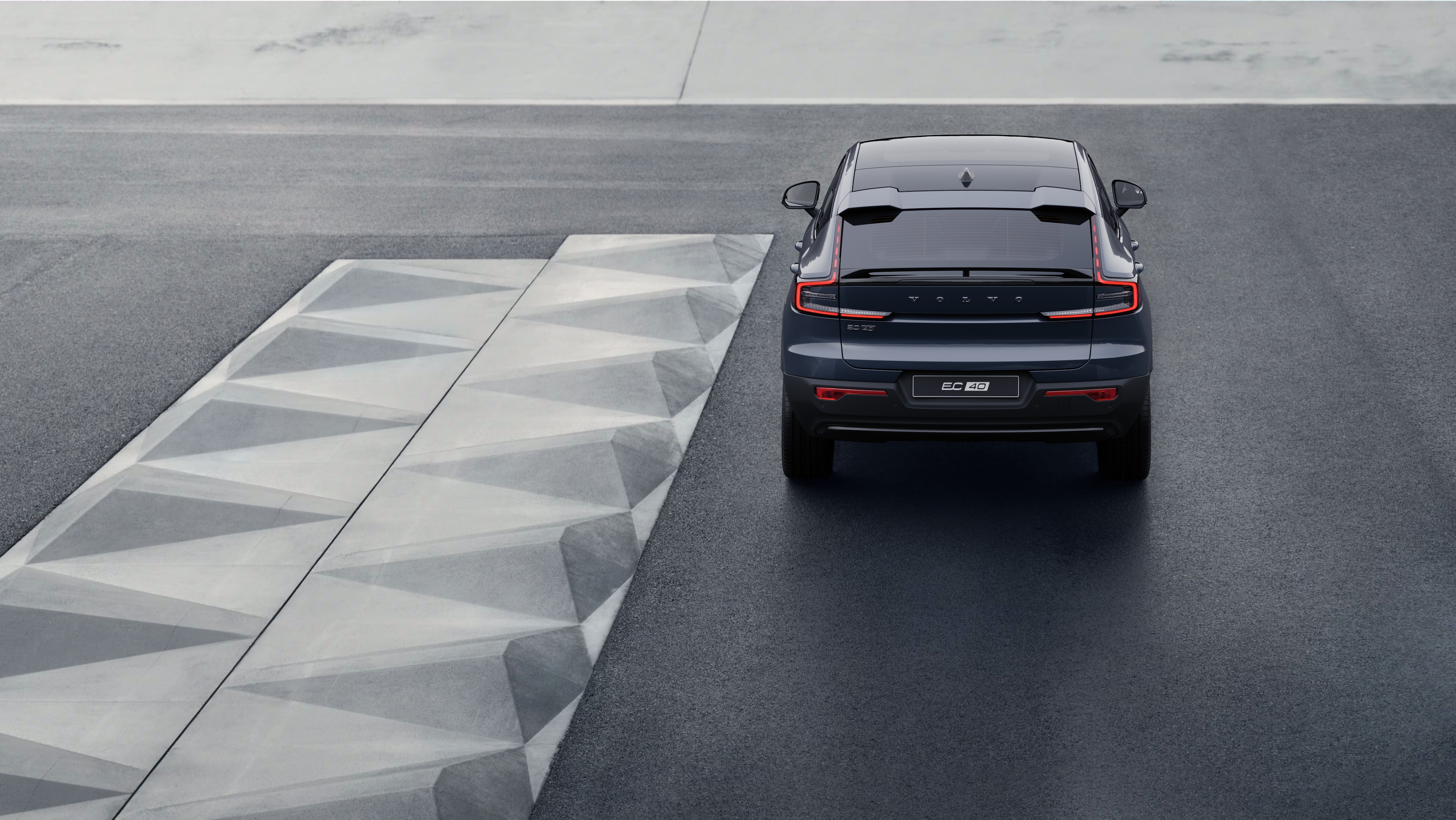 Achteraanzicht van een Volvo op een kronkelende kustweg met een strandachtergrond.