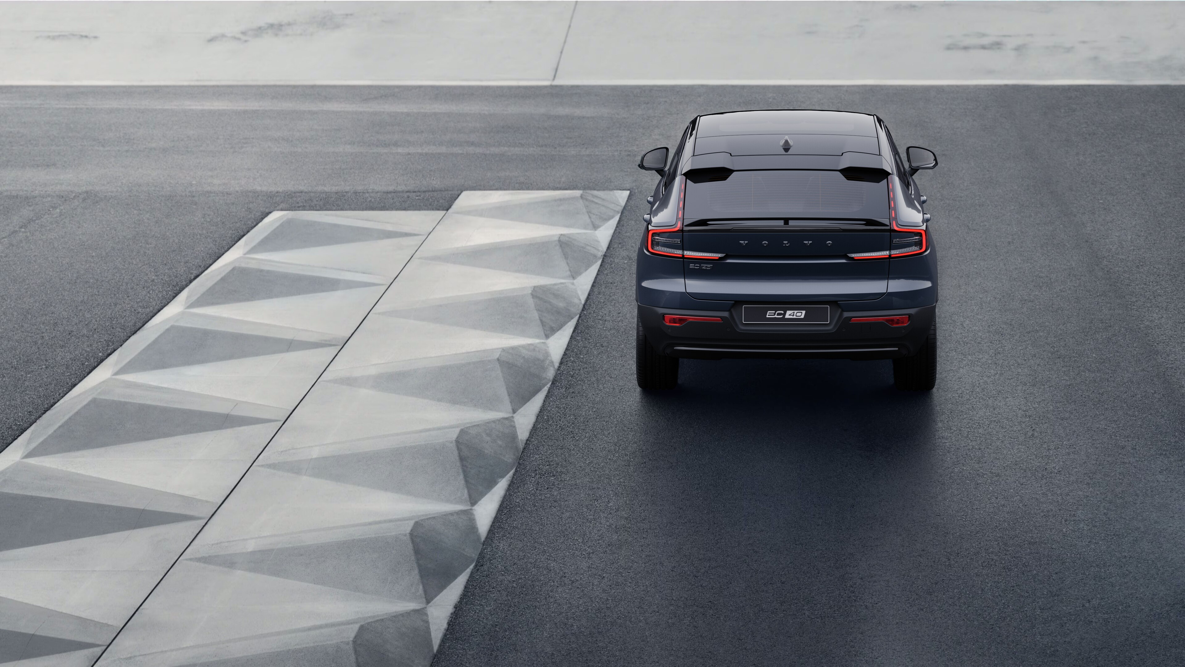 Volvo car rear view on a winding coastal road with a beachside background.