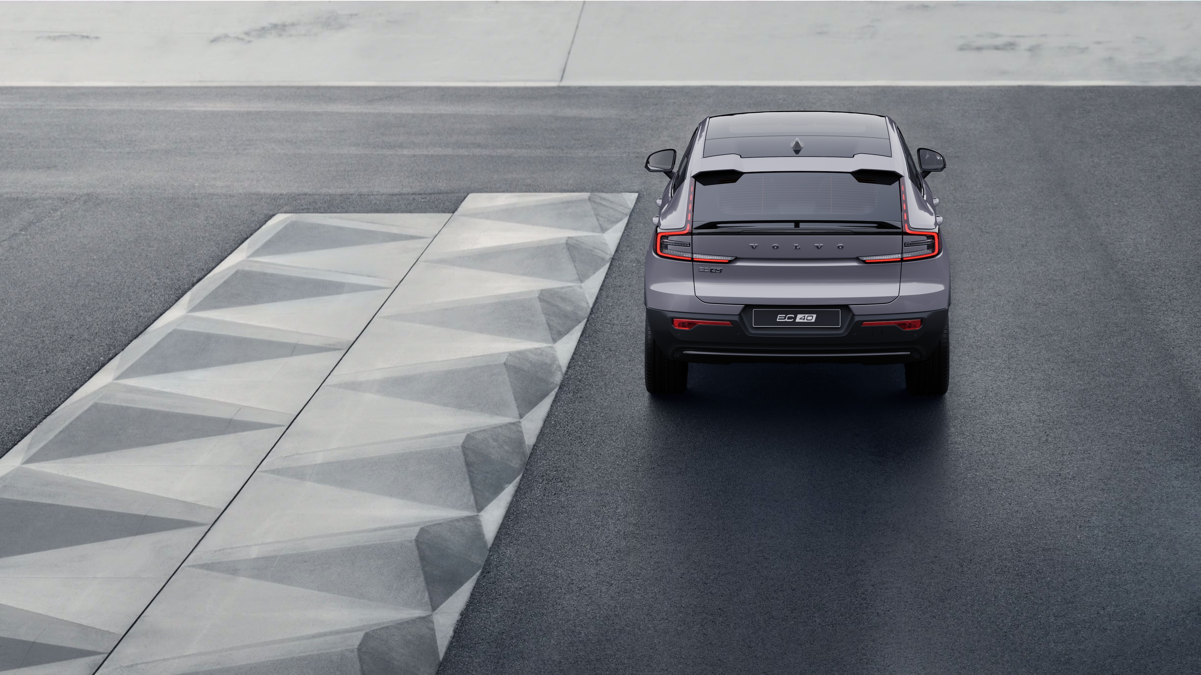 Volvo car rear view on a winding coastal road with a beachside background.
