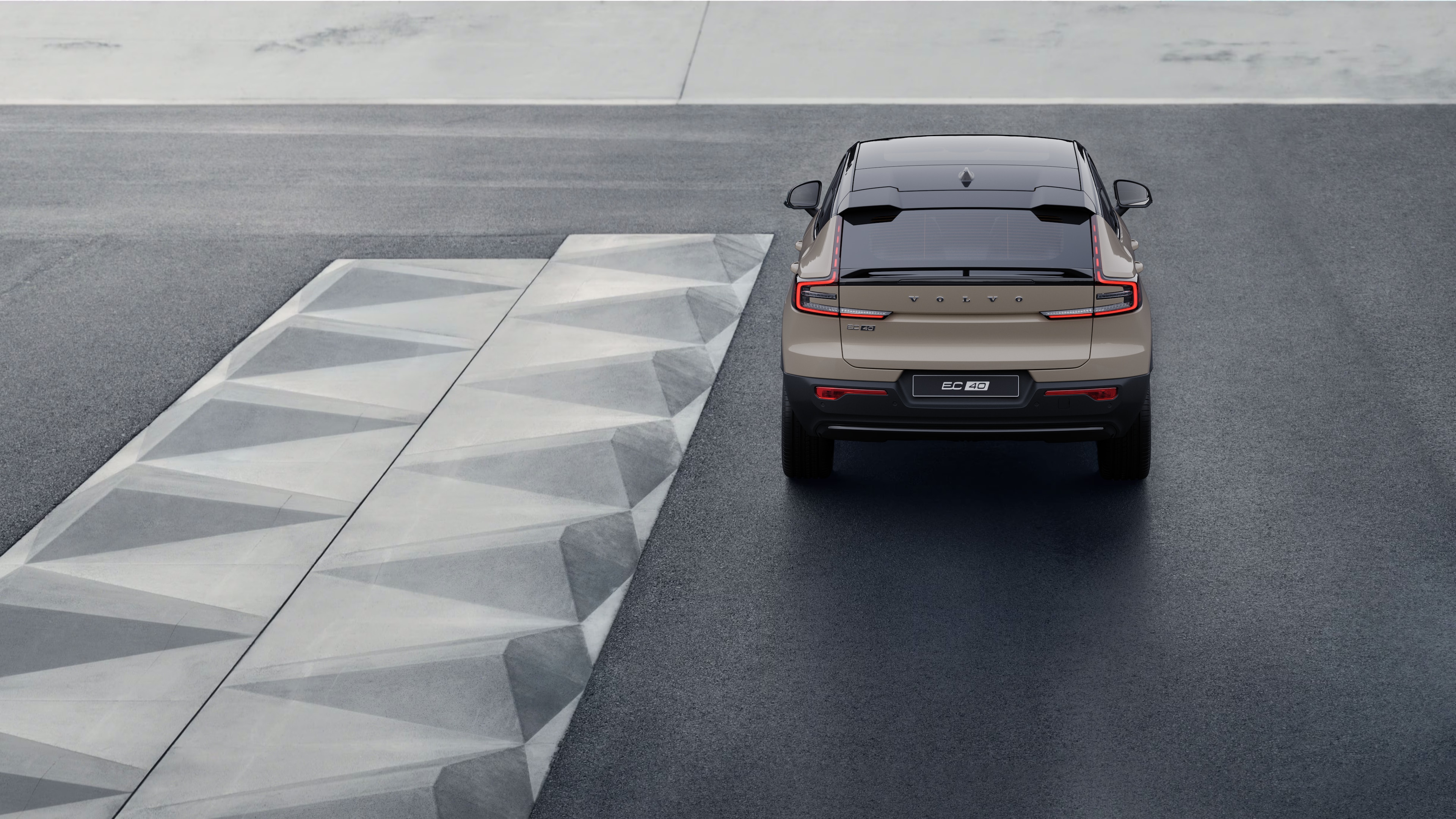 Volvo car rear view on a winding coastal road with a beachside background.