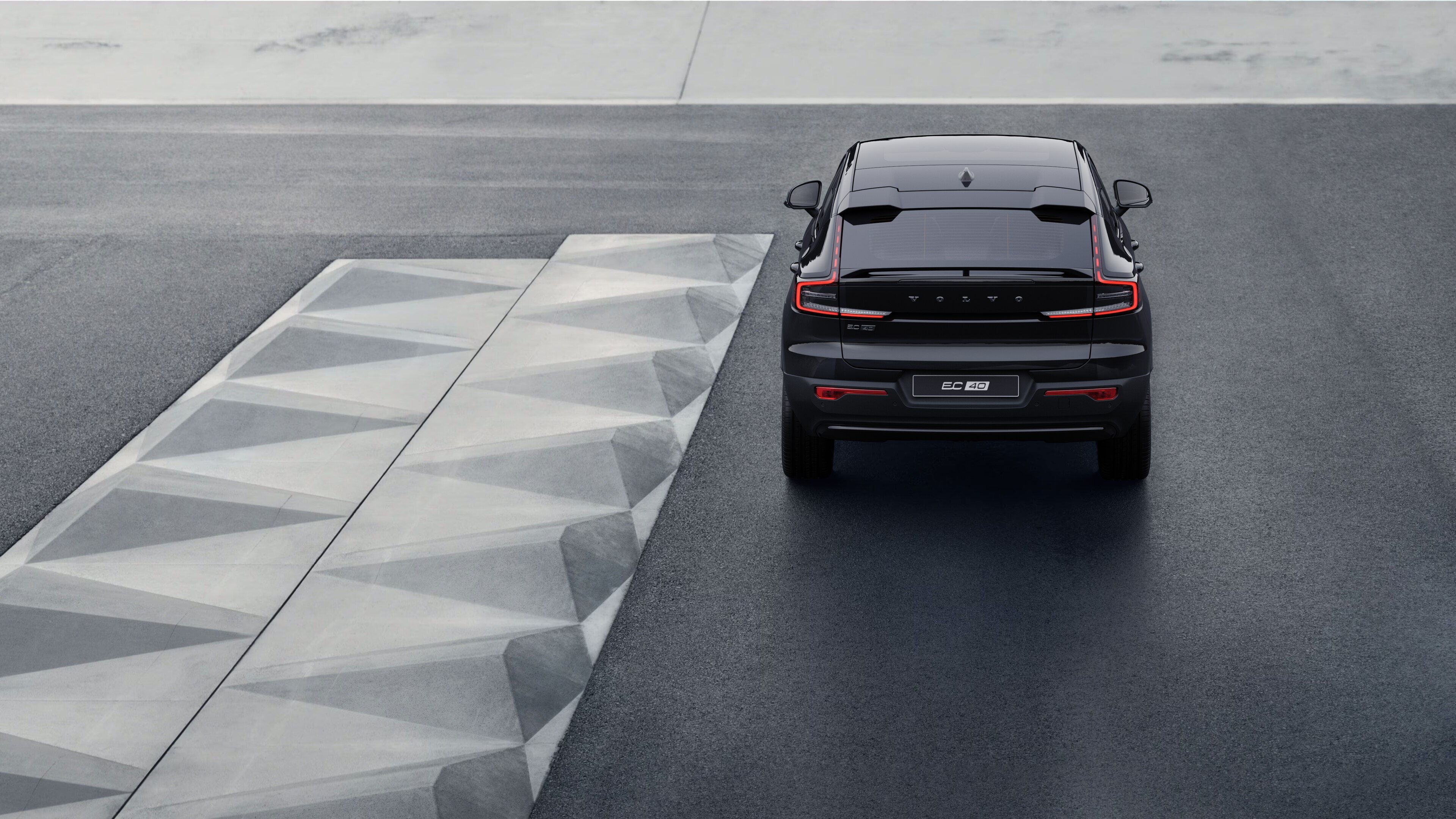 Volvo car rear view on a winding coastal road with a beachside background.