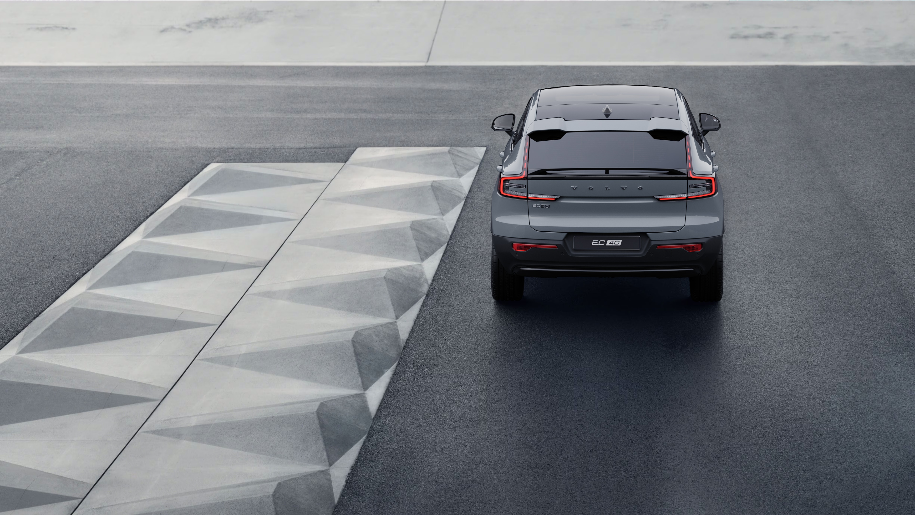 Vue arrière d’une Volvo sur une route côtière sinueuse en bord de mer.