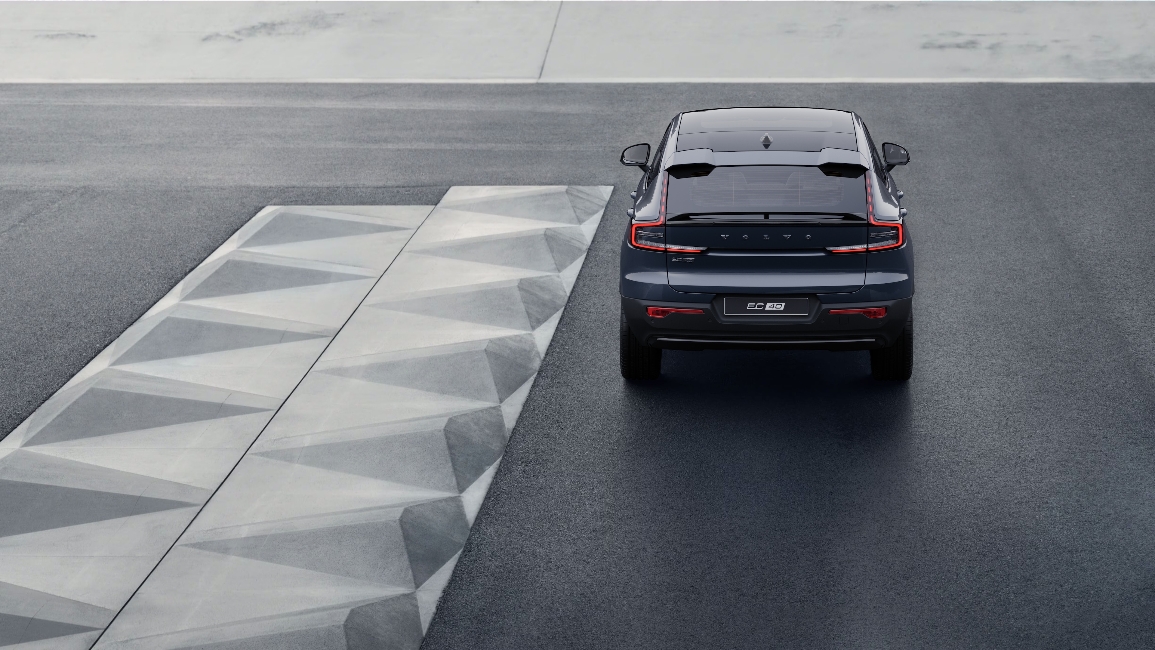 Vista traseira do carro Volvo em uma estrada costeira sinuosa com um fundo à beira-mar.