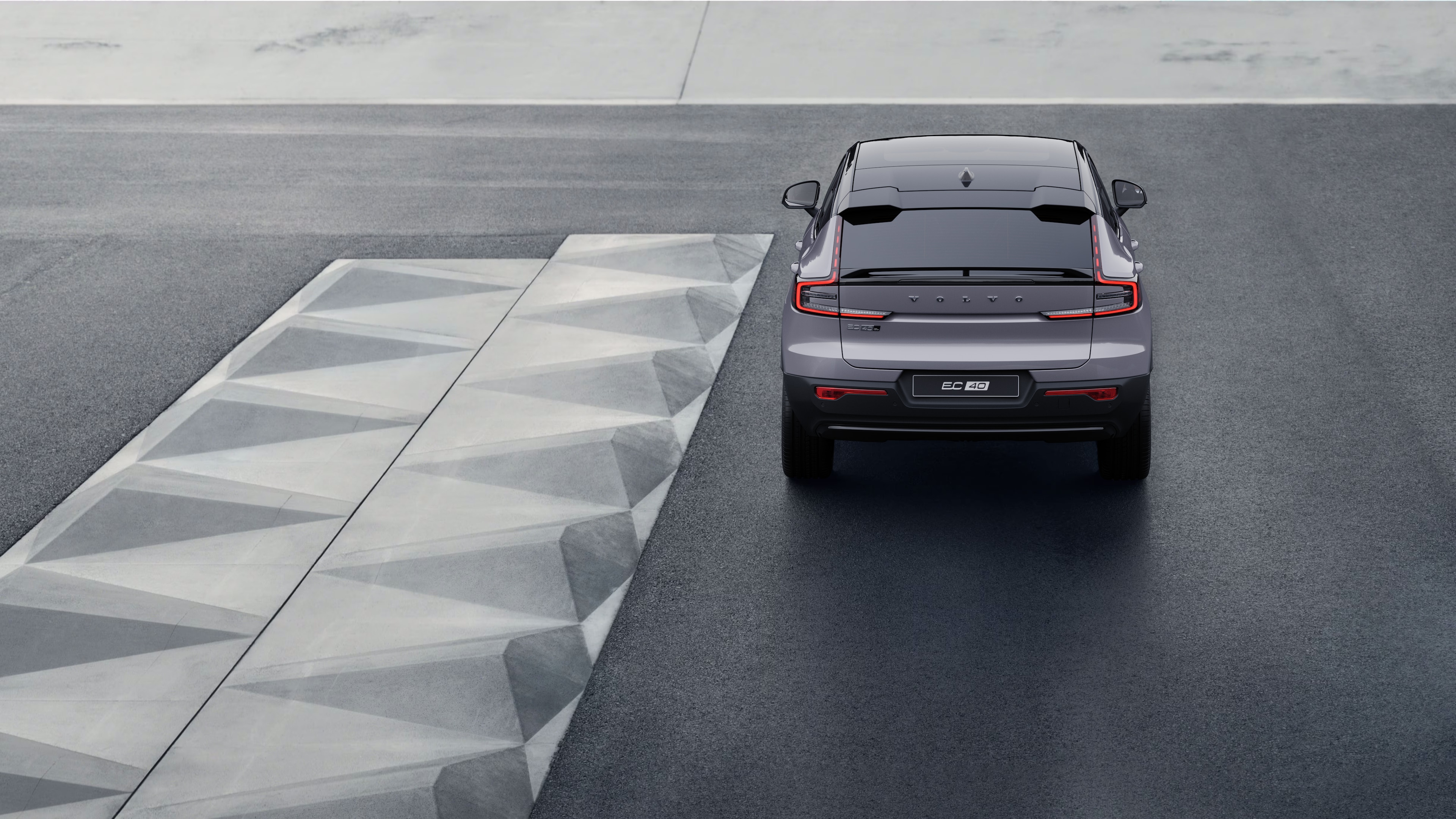 Vue arrière d’une voiture Volvo sur une route côtière sinueuse avec un arrière-plan en bord de mer.