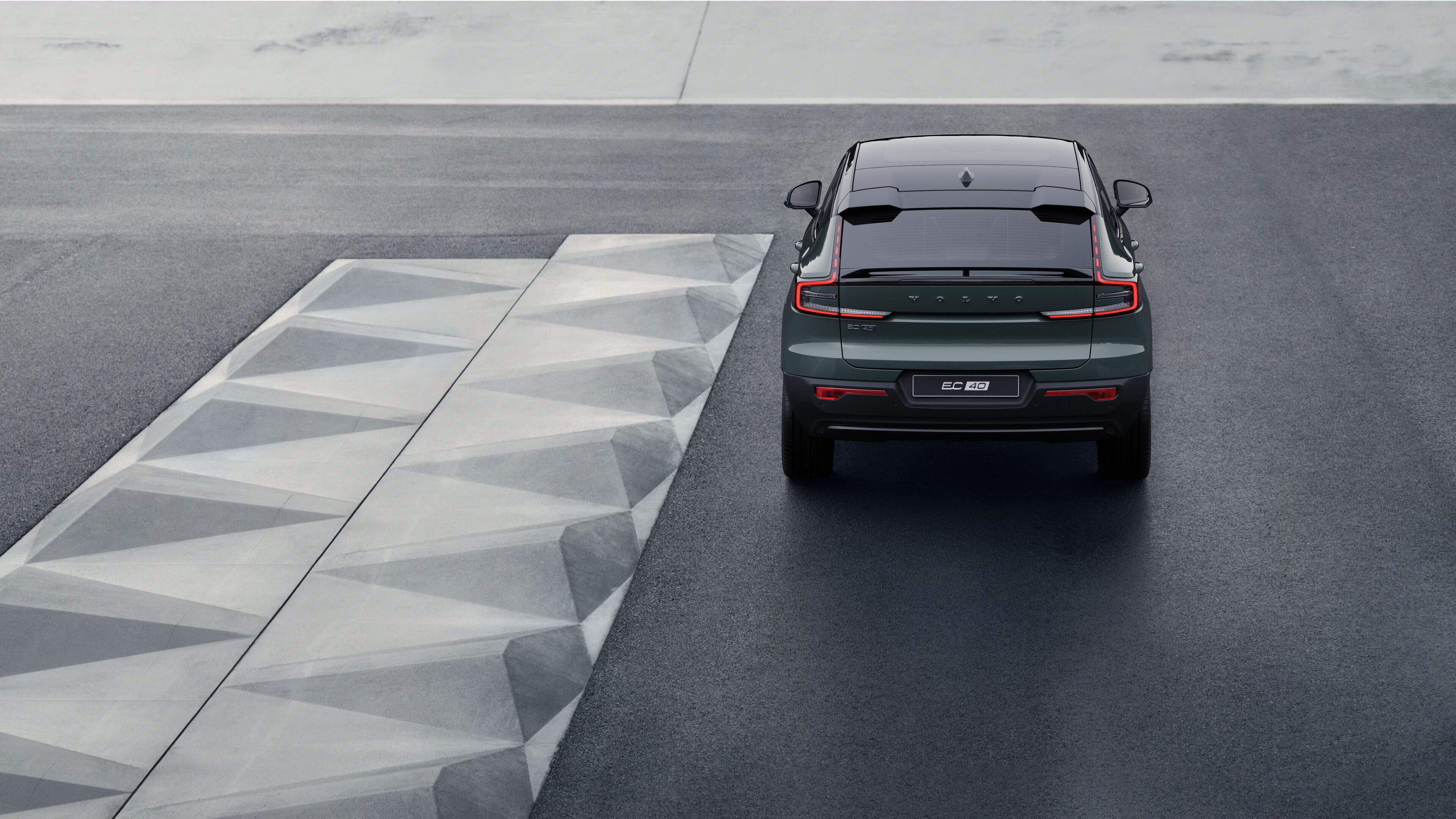 Volvo car rear view on a winding coastal road with a beachside background.