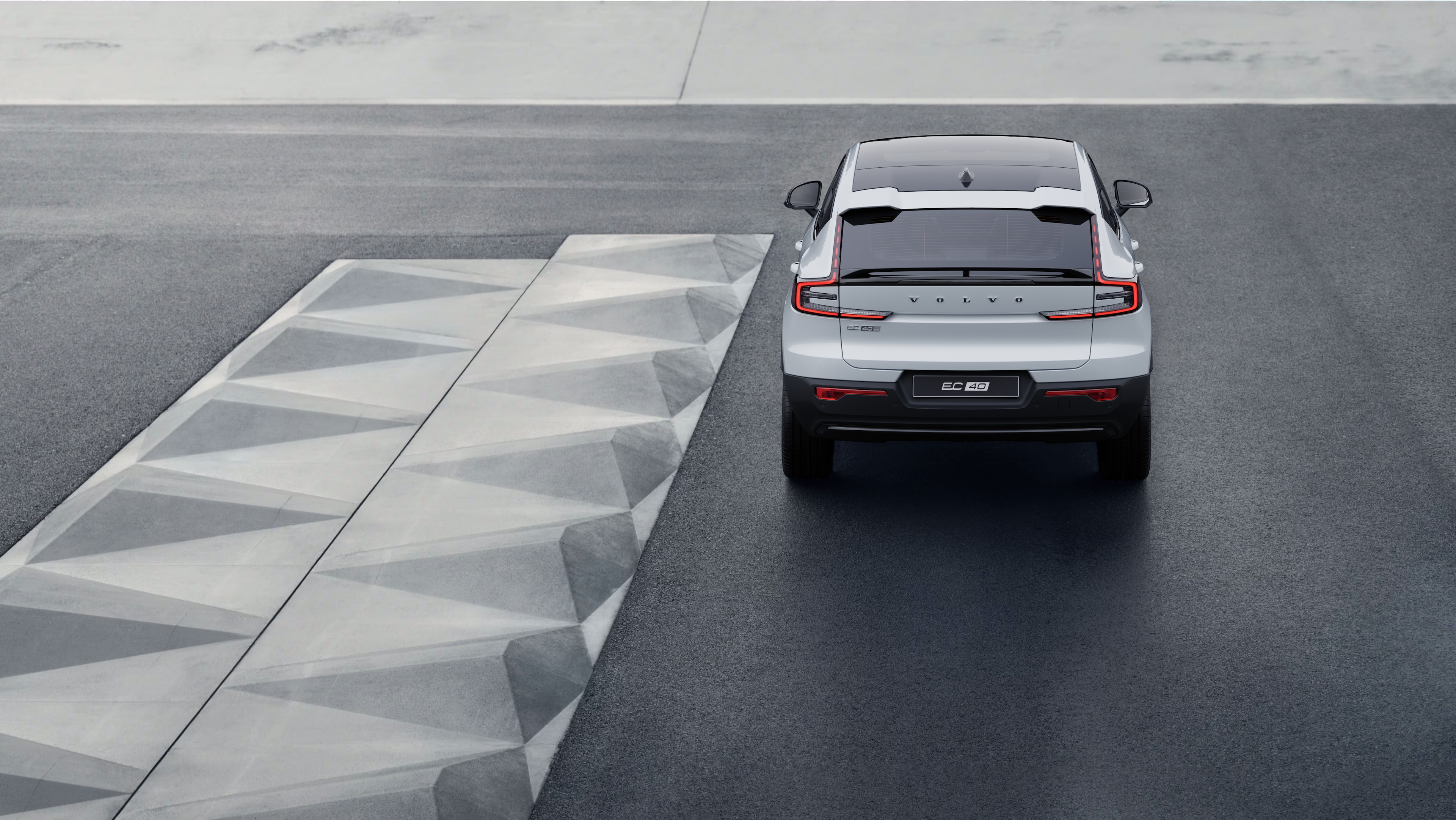 Volvo car rear view on a winding coastal road with a beachside background.