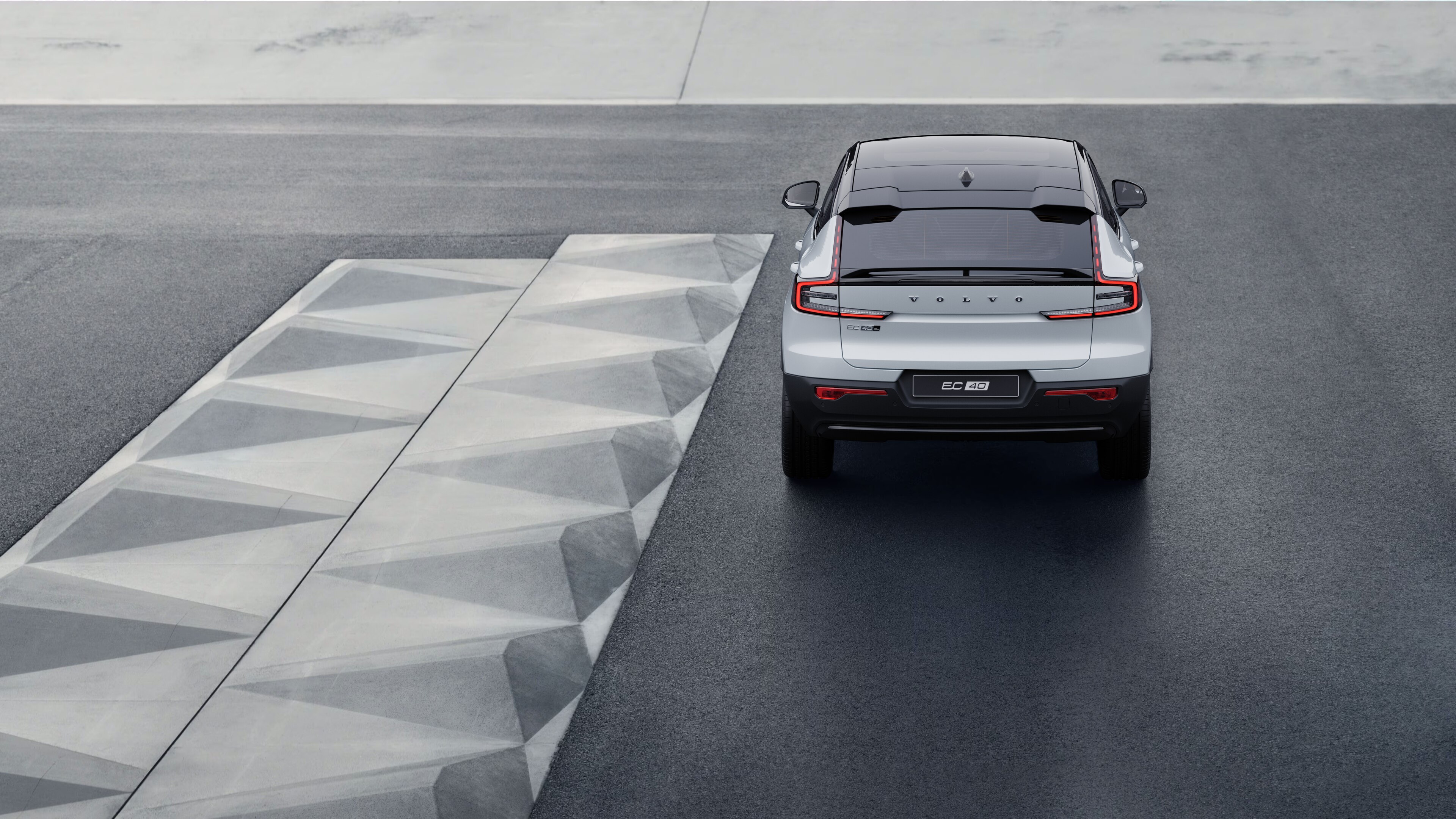 Arka planı sahil kenarında olan virajlı bir sahil yolunda Volvo aracın arkadan görünümü.