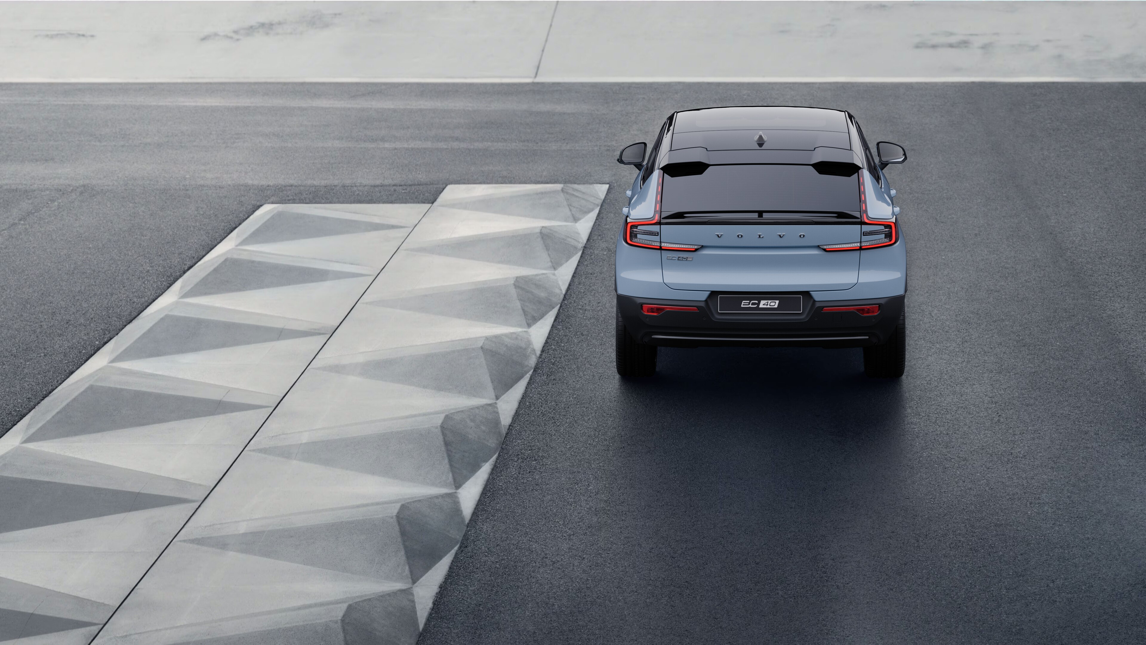Volvo car rear view on a winding coastal road with a beachside background.