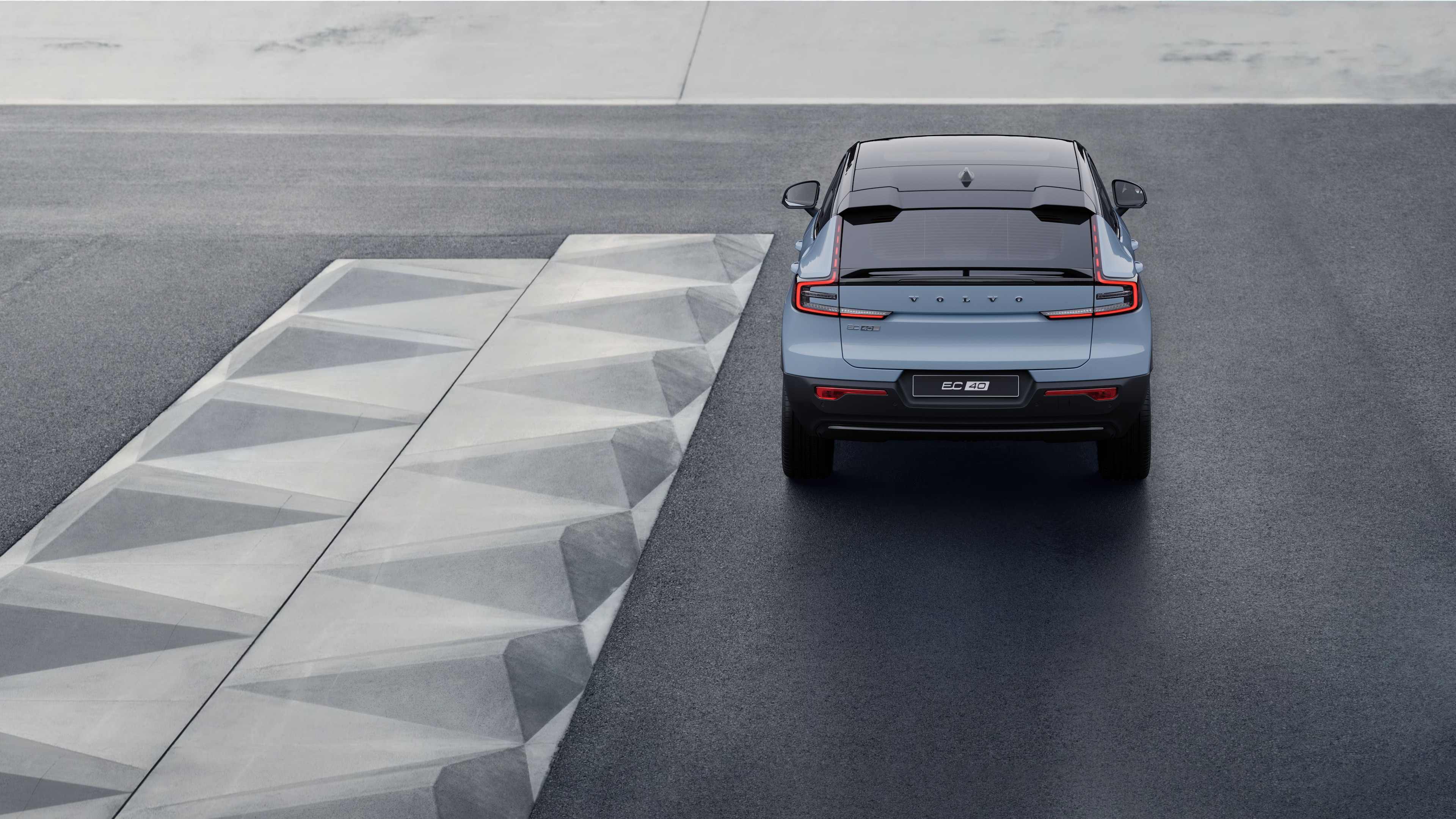 Volvo-bil set bagfra på en snoet kystvej med en strandbaggrund.