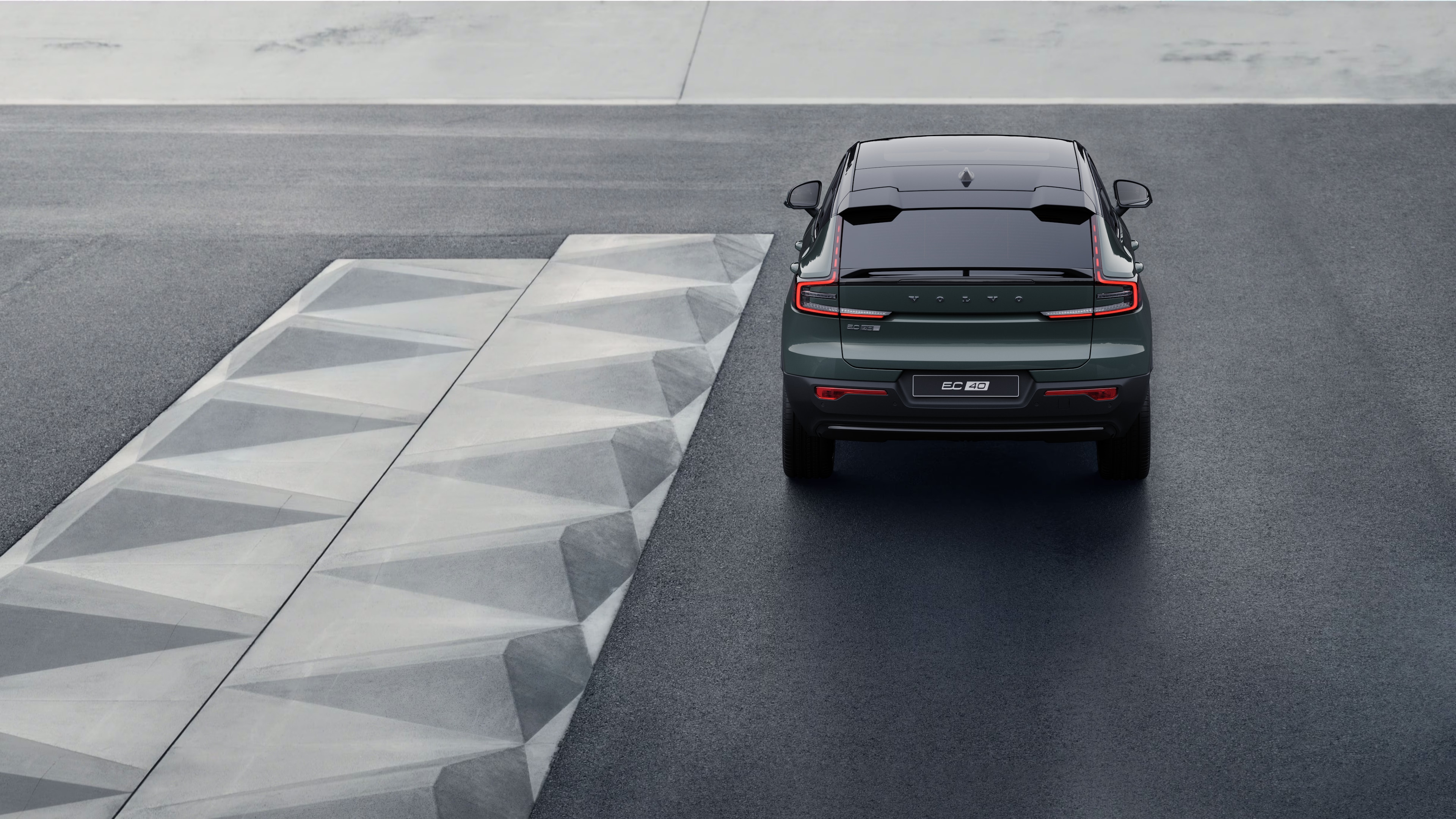Volvo car rear view on a winding coastal road with a beachside background.