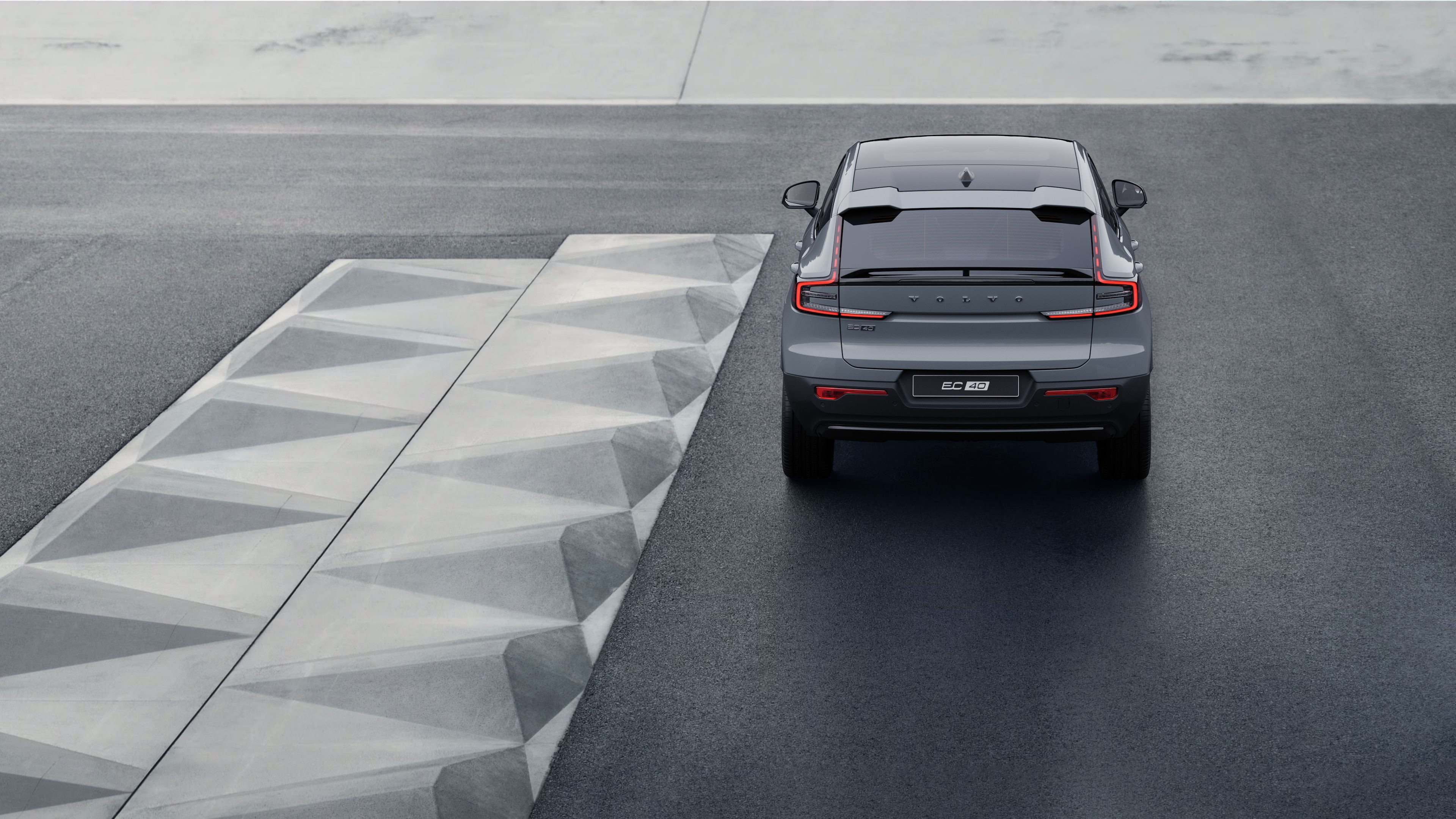 Vista traseira do automóvel Volvo numa estrada costeira sinuosa com fundo à beira-mar.