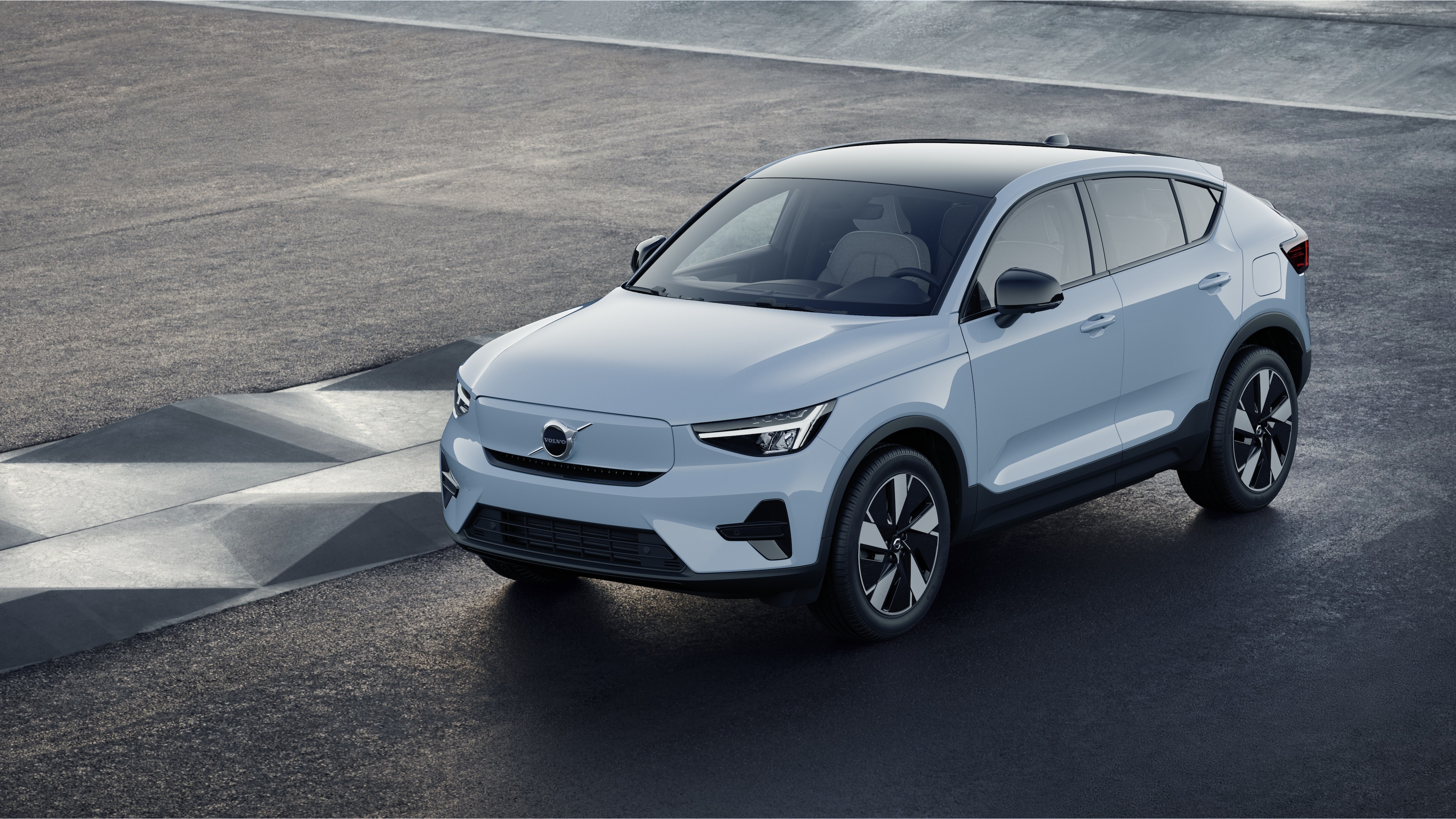 Exterior do carro Volvo em vista de três quartos contra um fundo de parede de concreto industrial.