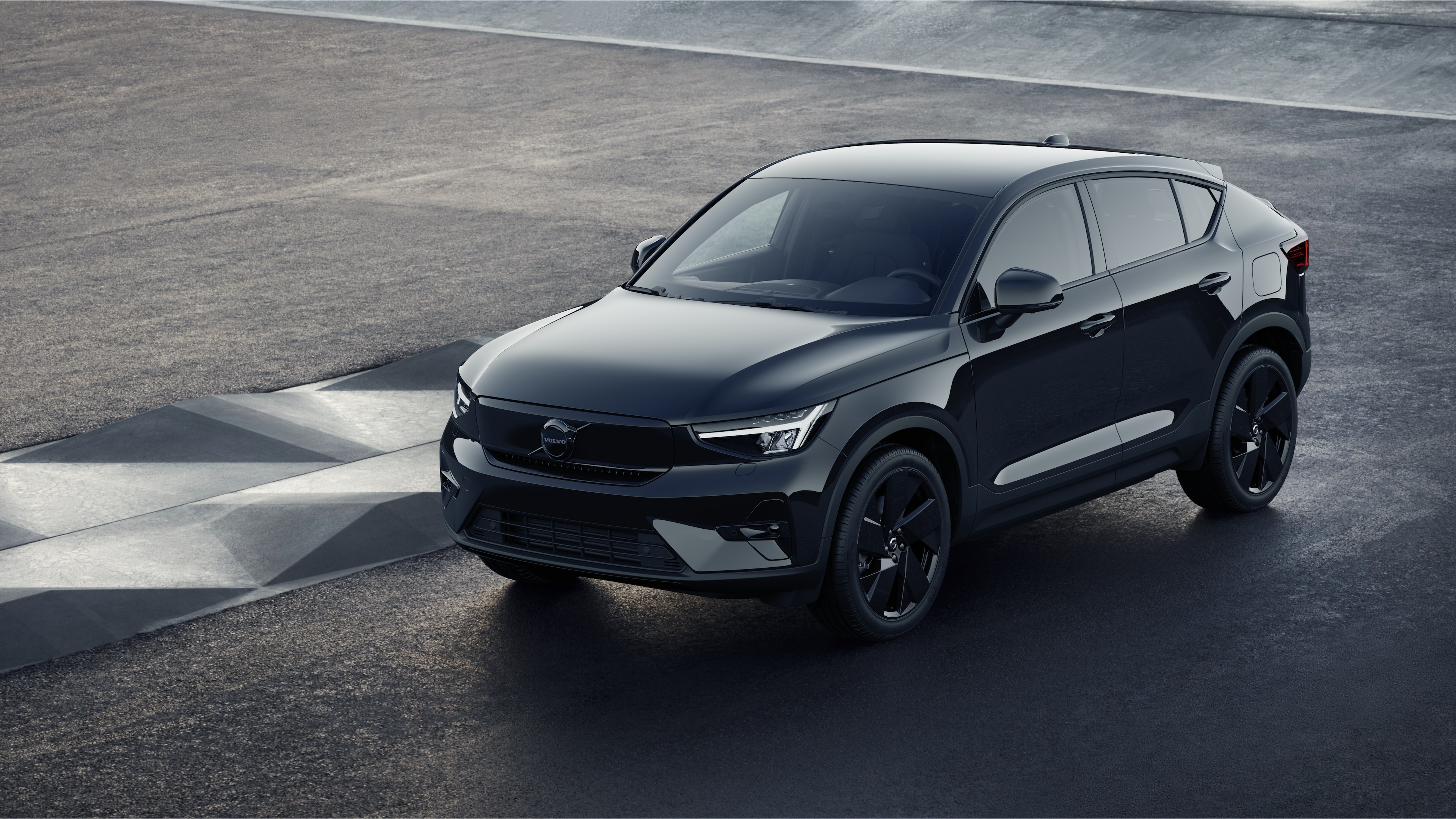 Volvobilens exteriör i trekvartsvy mot en industriell betongväggsbakgrund.