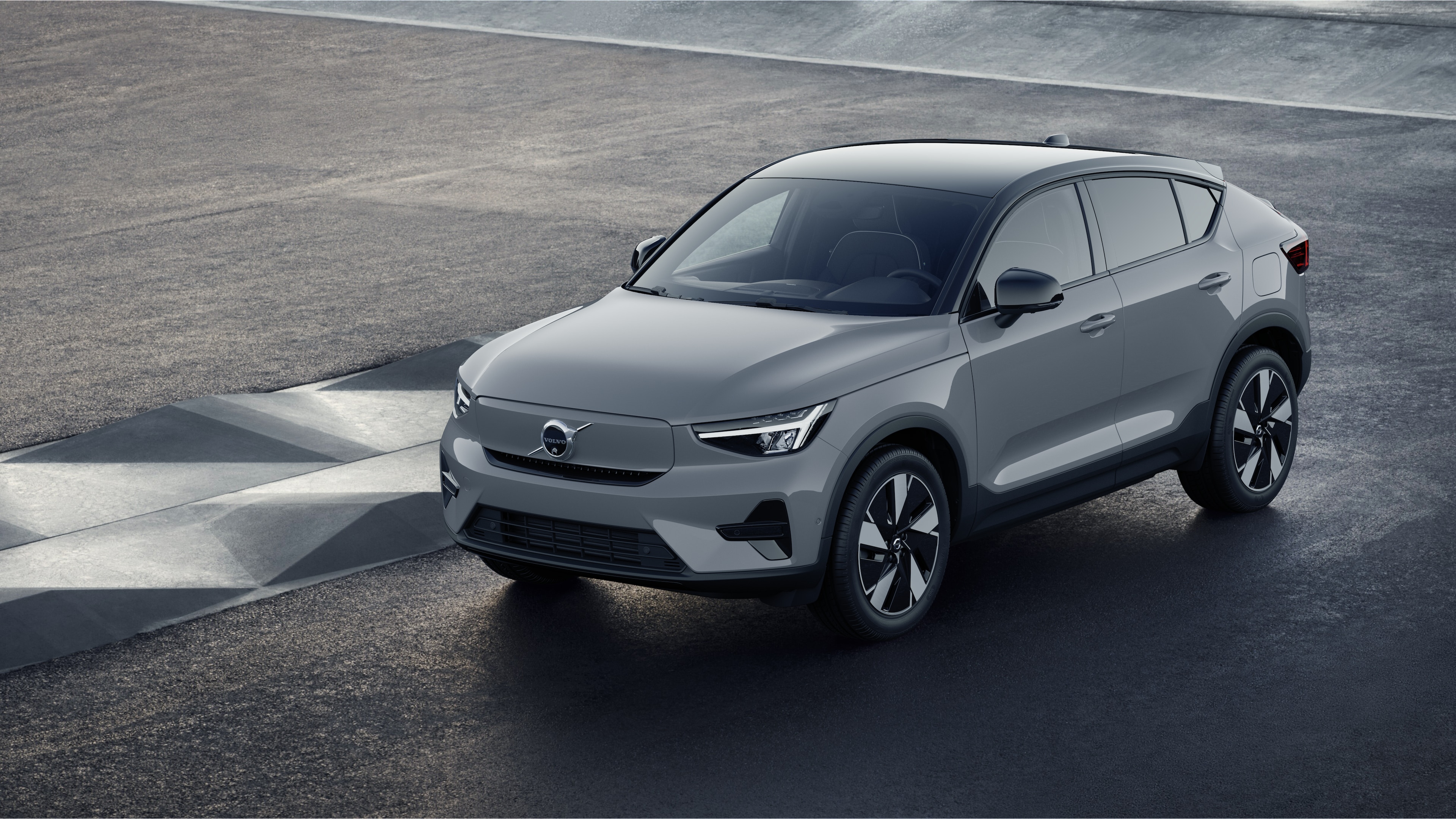 Extérieur d’une Volvo vue de trois quarts sur un fond de mur industriel en béton.