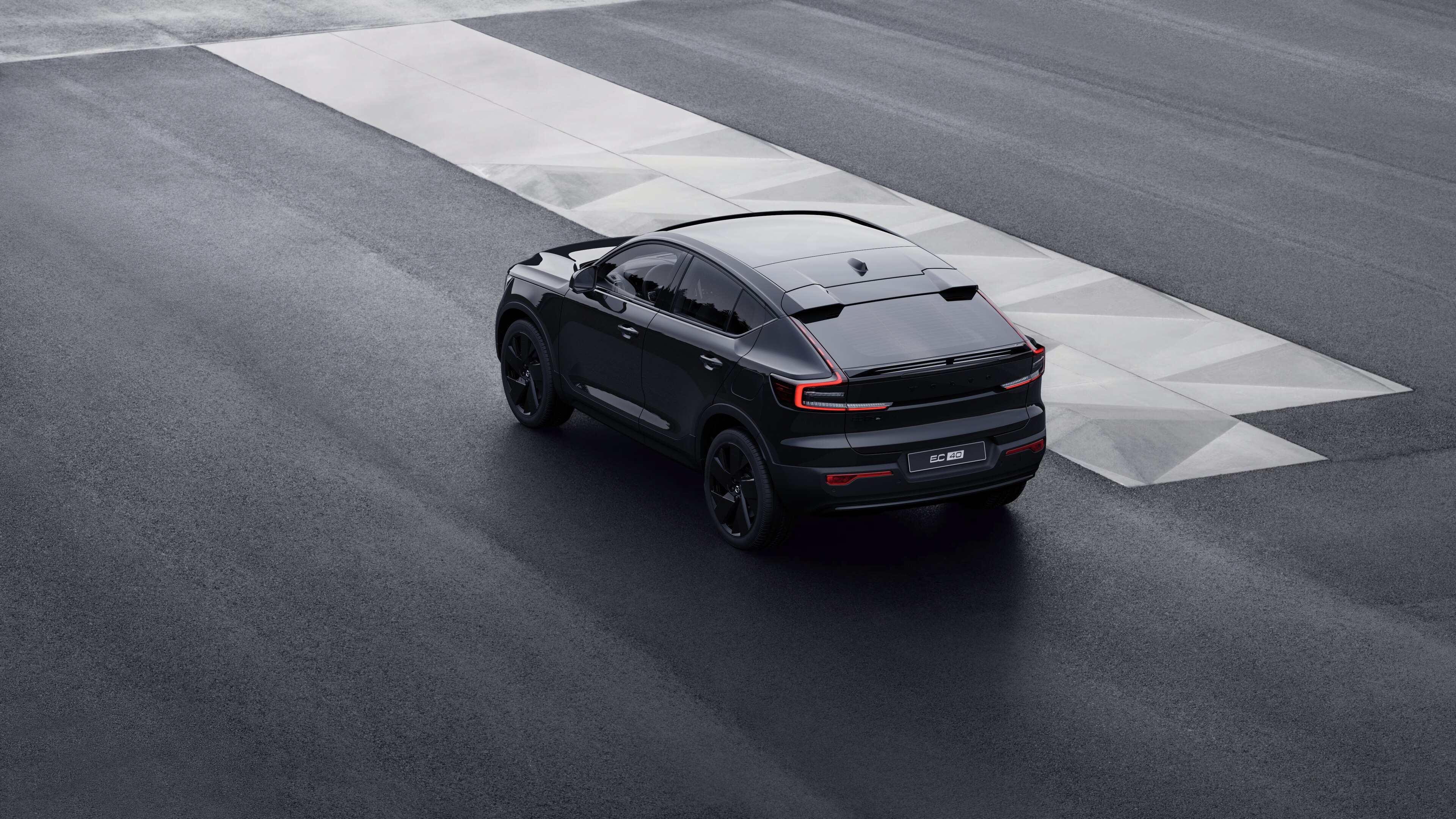 Volvo-bíll að aftan, séð þrjá fjórðu hluta úr bíl, lagt við steyptan vegg á götu í borg.