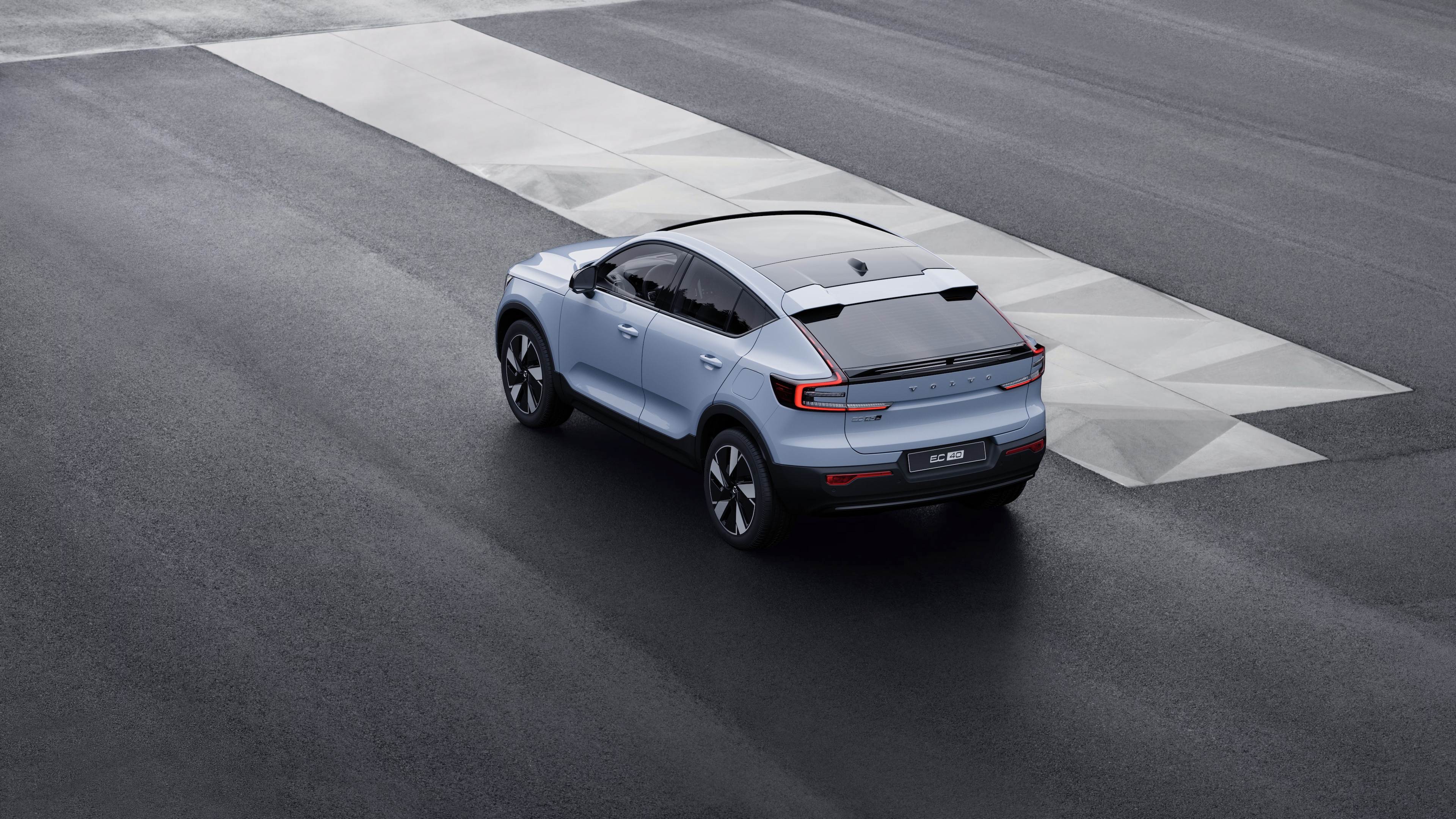 Volvo-bíll að aftan, séð þrjá fjórðu hluta úr bíl, lagt við steyptan vegg á götu í borg.