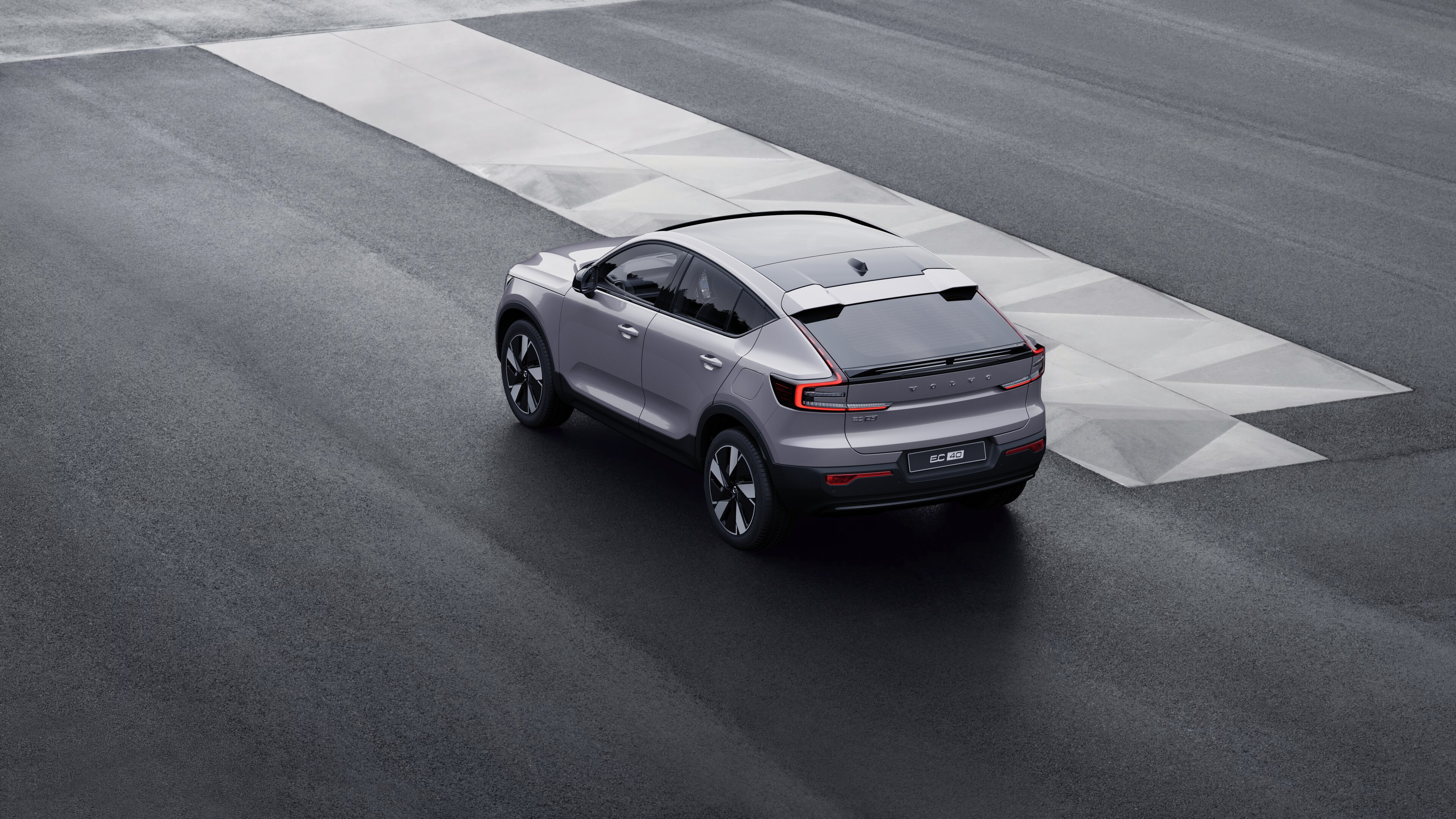 Volvo car in rear three-quarter view parked against a concrete wall on an urban street background.