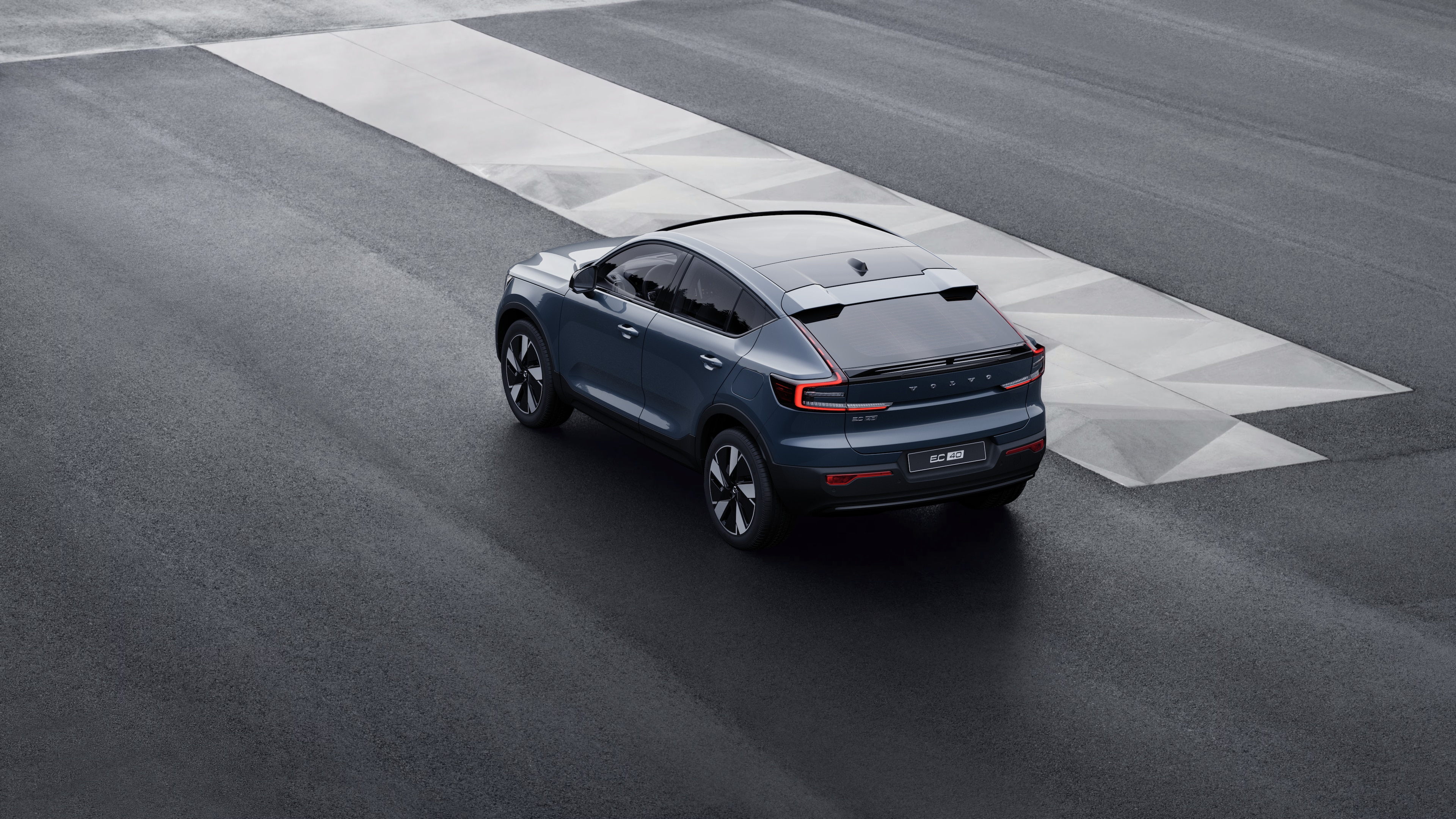 Volvo-auto in driekwart achteraanzicht geparkeerd tegen een betonnen muur op een stedelijke straatachtergrond.