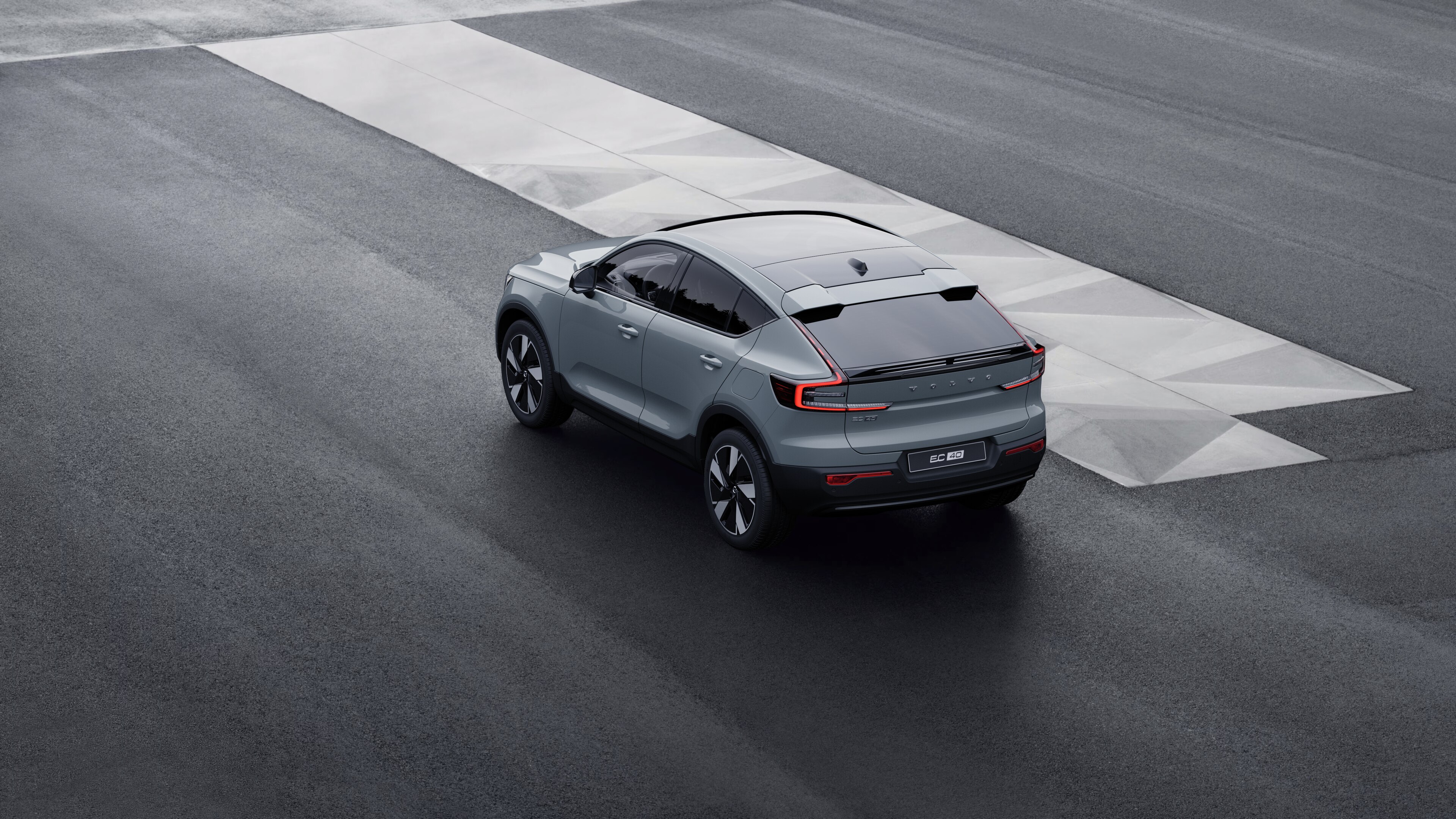 Driekwart achteraanzicht van een Volvo-auto geparkeerd tegen een betonnen muur op de achtergrond van een stedelijke straat.