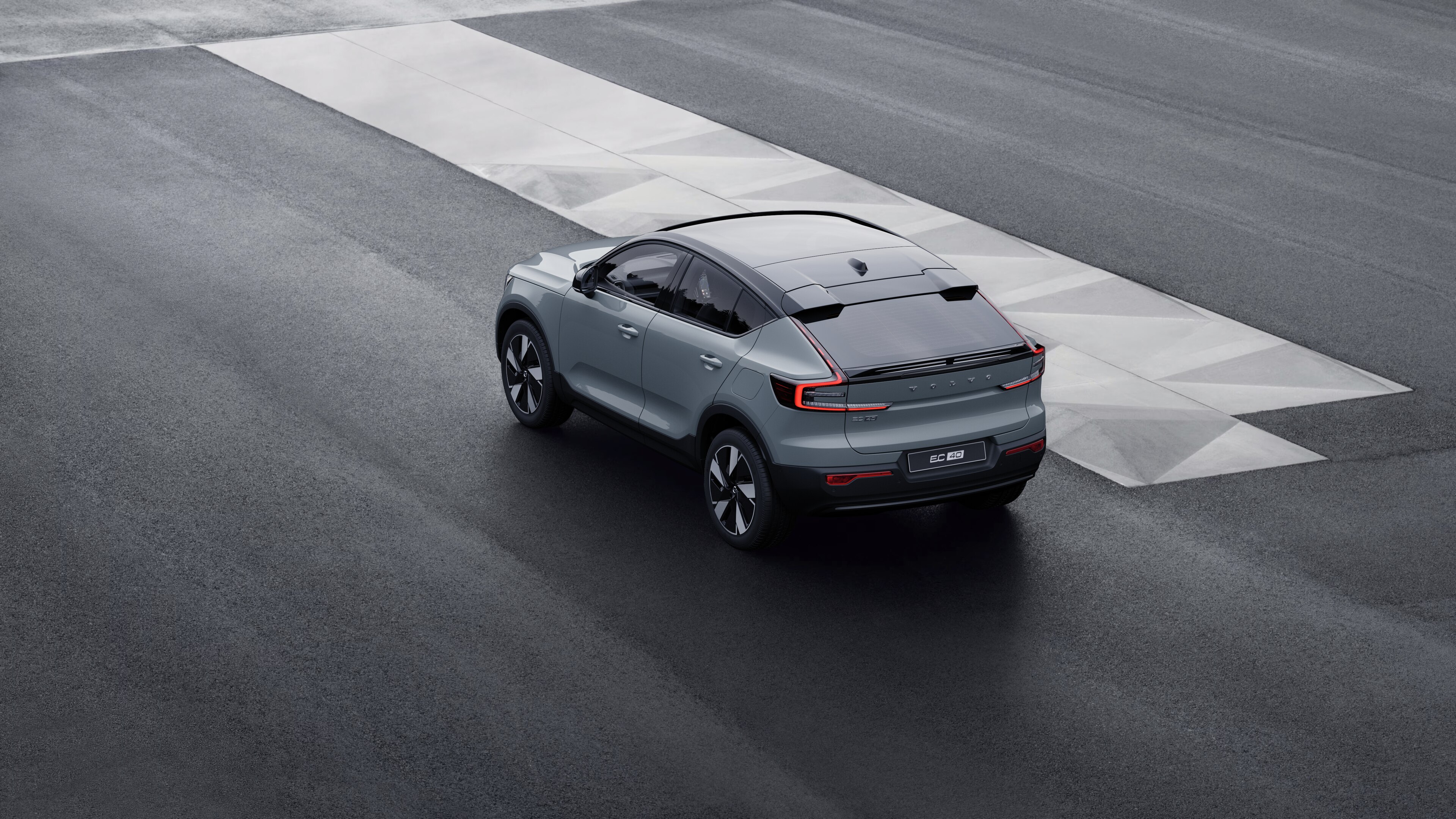 Volvo car in rear three-quarter view parked against a concrete wall on an urban street background.