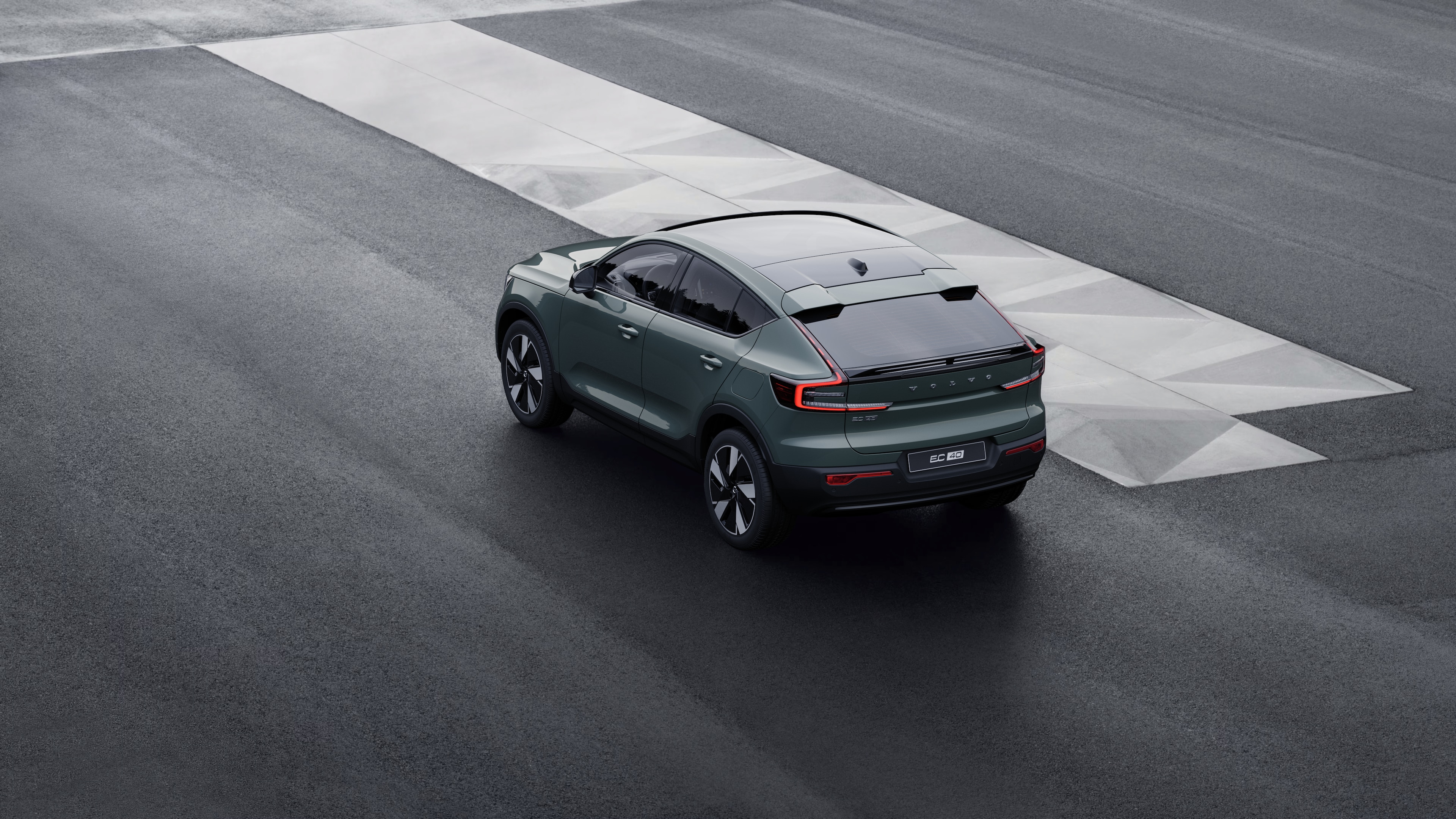 Volvo-auto in driekwart achteraanzicht geparkeerd tegen een betonnen muur op een stedelijke straatachtergrond.