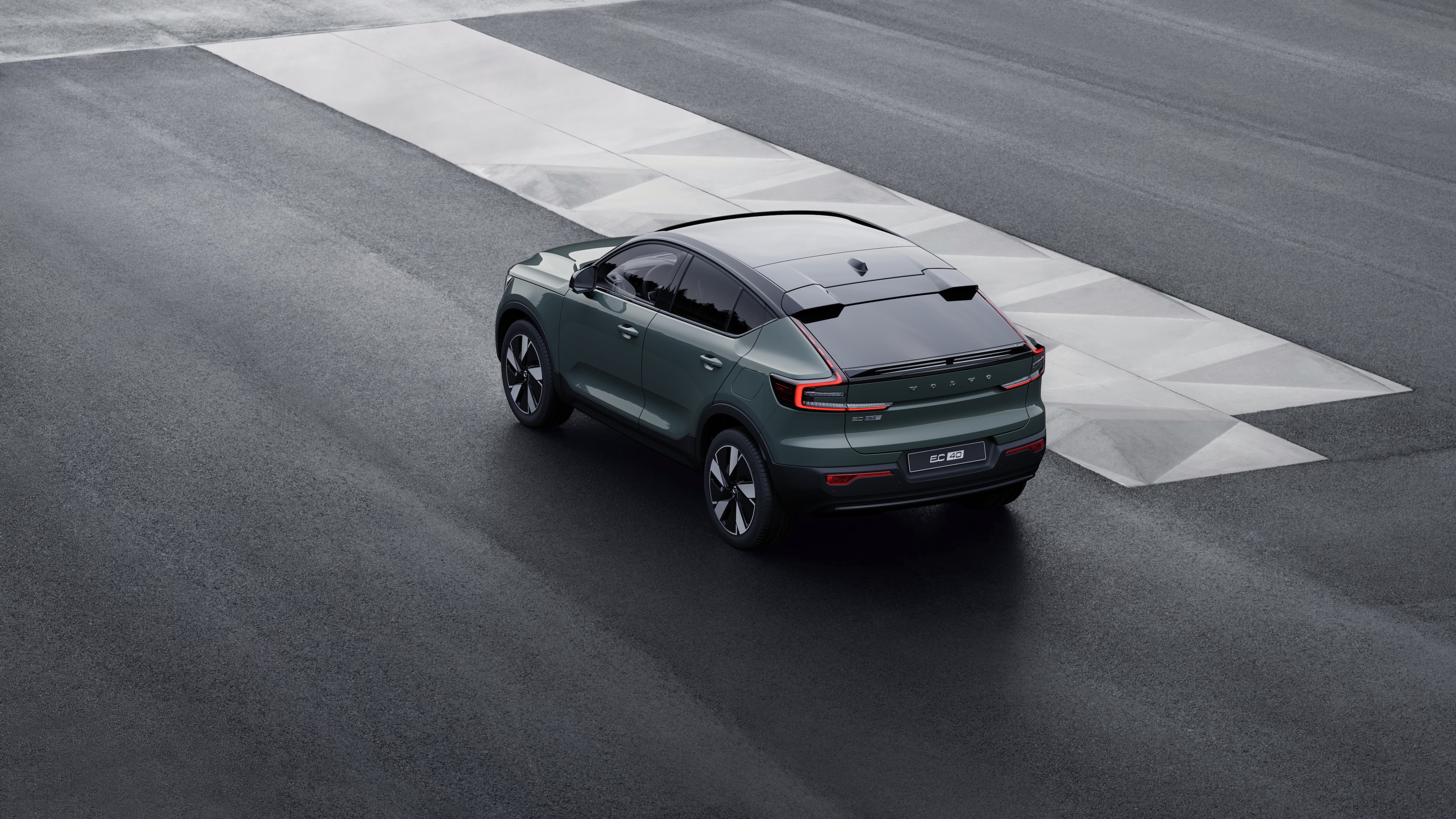 Vue arrière d’une Volvo de trois quarts, garée contre un mur de béton sur un fond de rue urbaine.