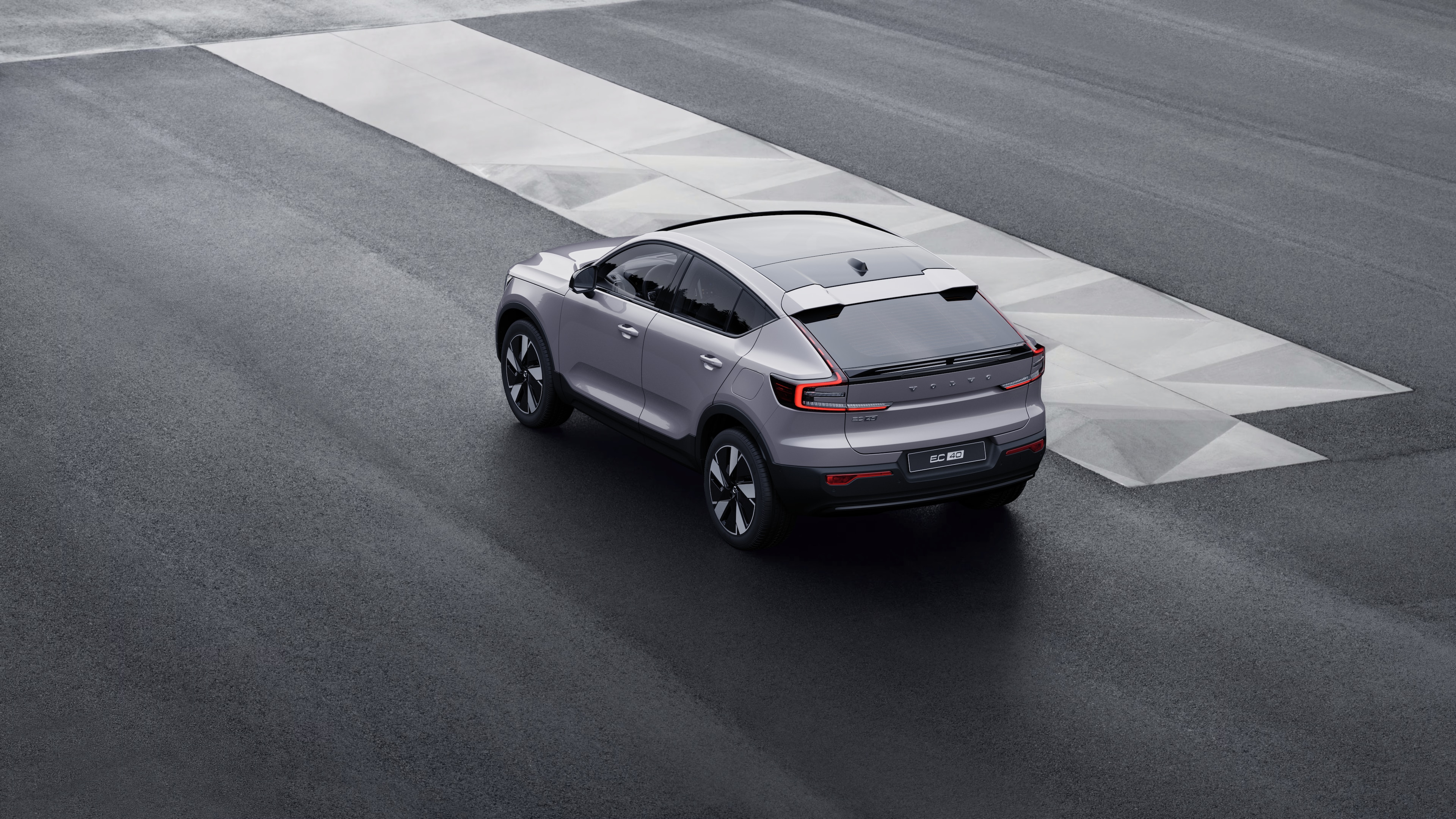 Volvo car in rear three-quarter view parked against a concrete wall on an urban street background.