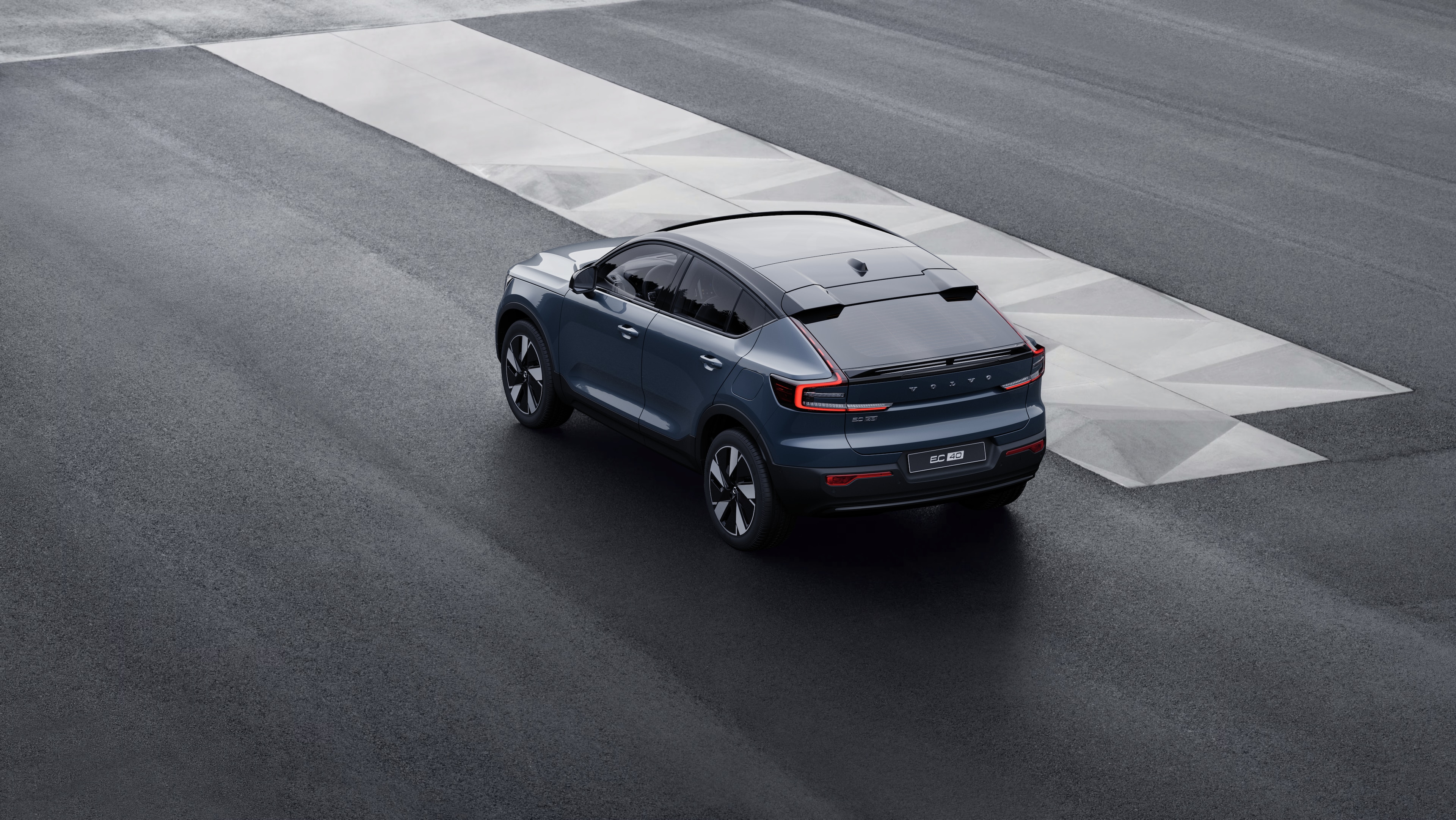 Samochód Volvo w widoku z tyłu w trzech czwartych zaparkowany przy murze na tle miejskiej ulicy