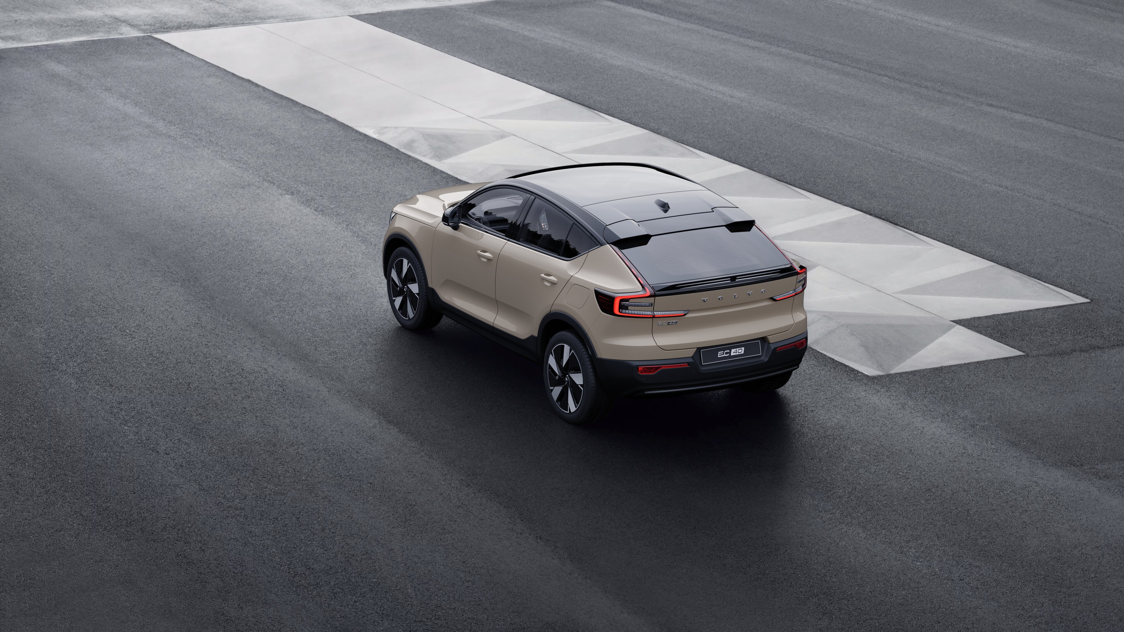 Volvo car in rear three-quarter view parked against a concrete wall on an urban street background.