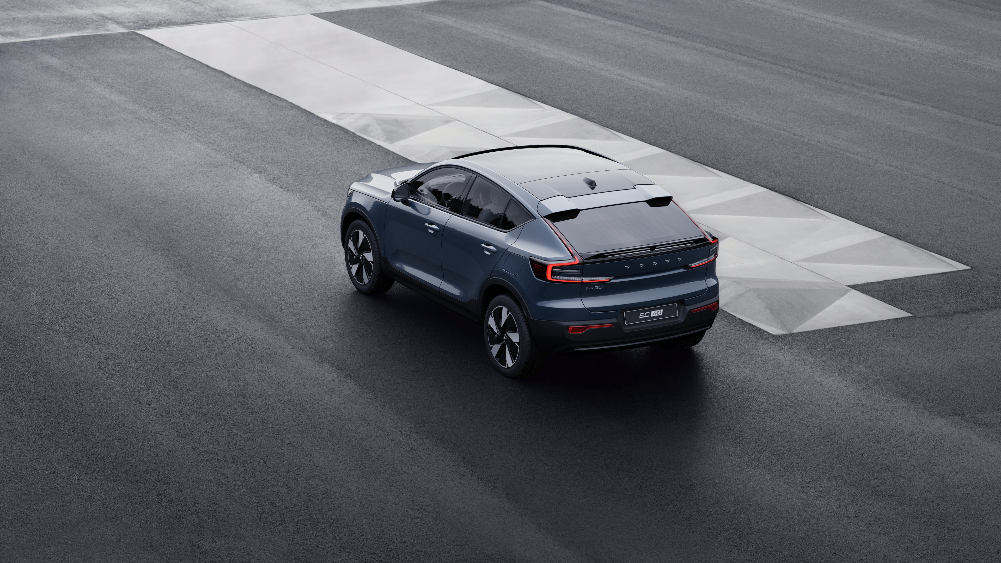 Carro Volvo na traseira estacionado contra uma parede de concreto em um fundo de rua urbana.