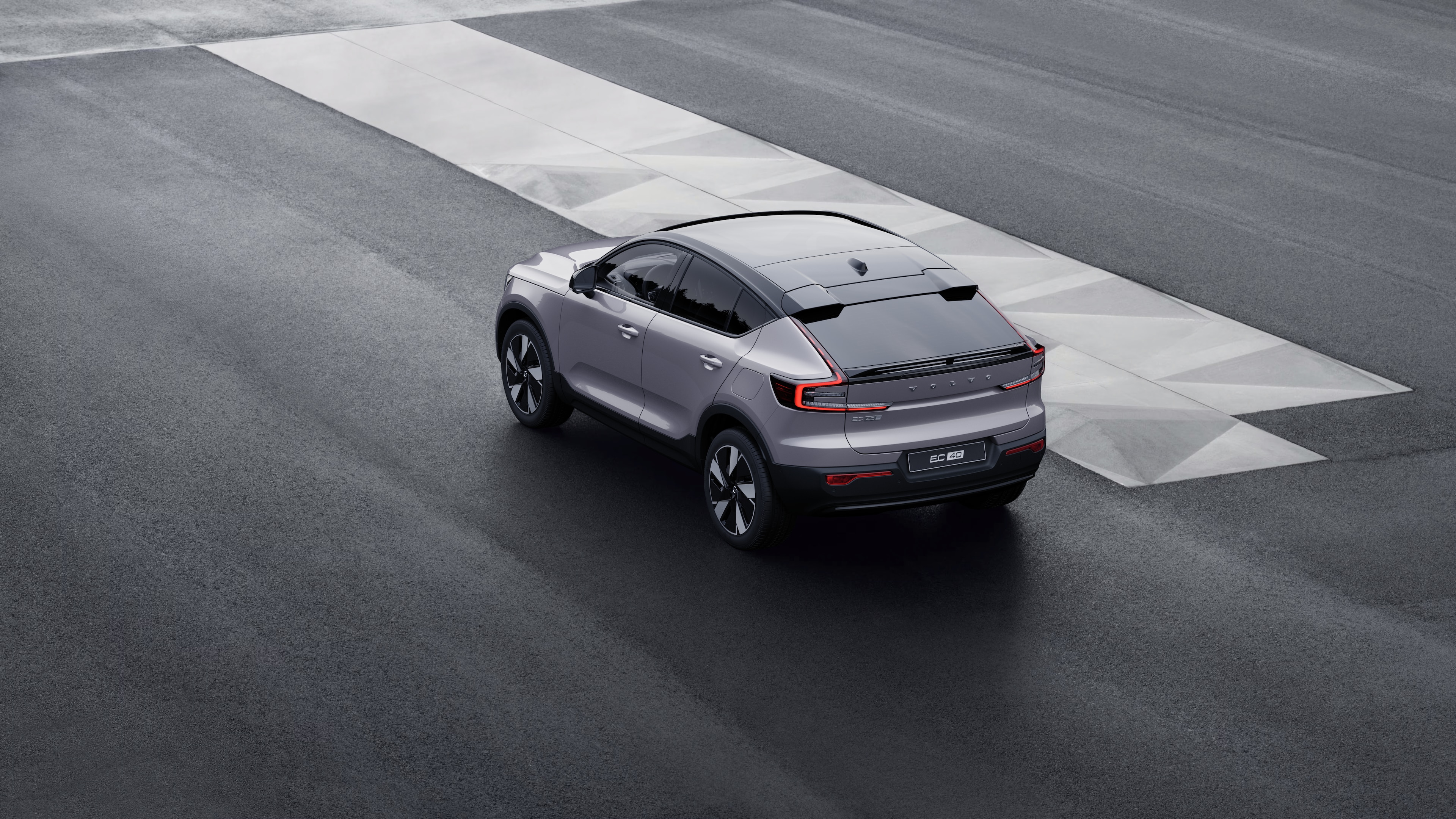 Vue arrière d’une Volvo de trois quarts, garée contre un mur de béton sur un fond de rue urbaine.