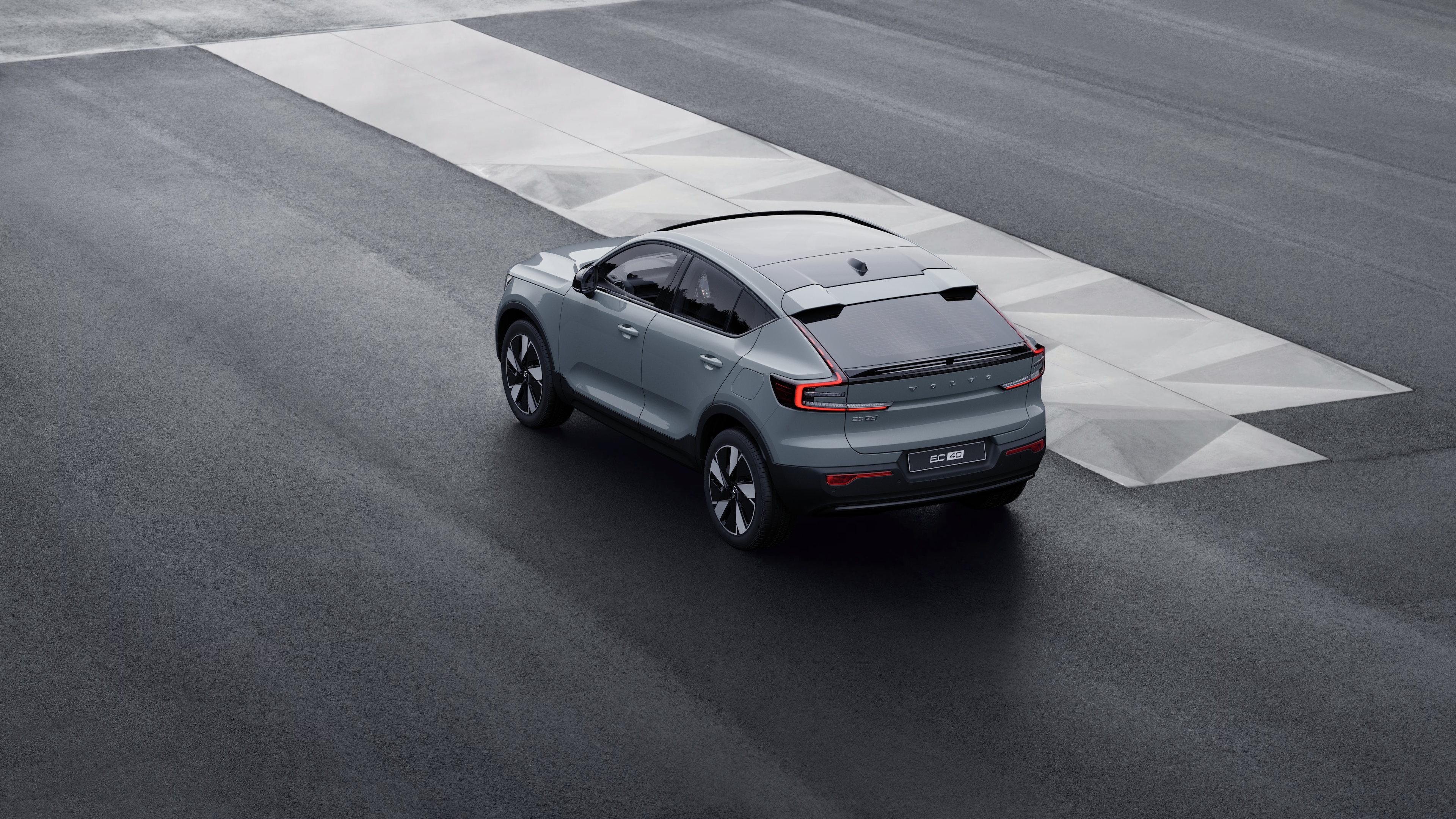 Volvo car in rear three-quarter view parked against a concrete wall on an urban street background.