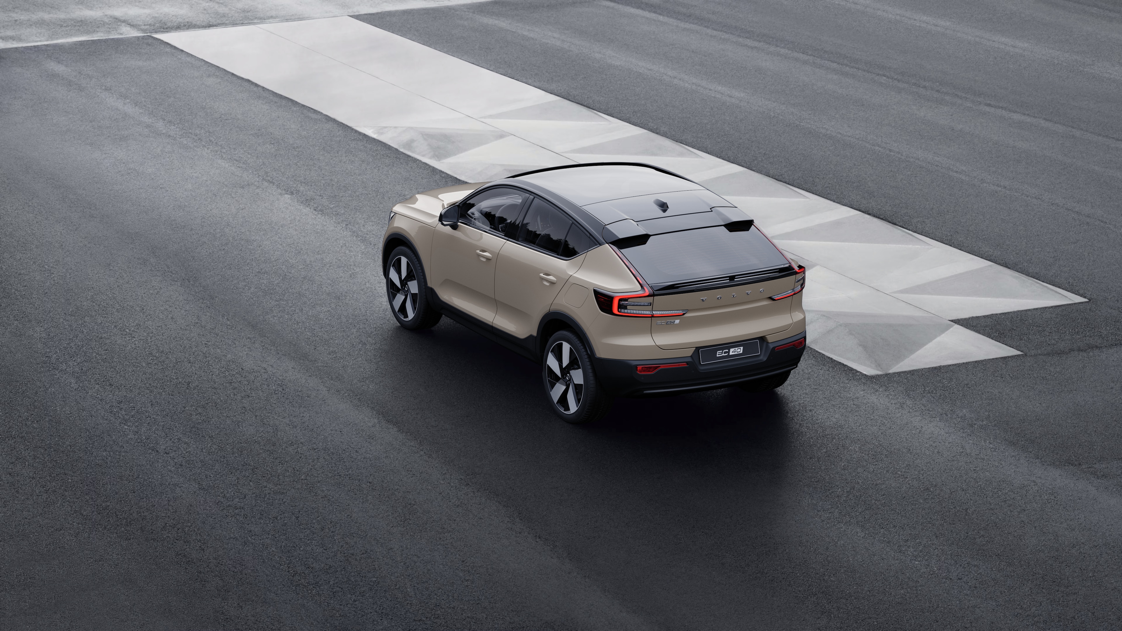 Vehículo Volvo en vista trasera de tres cuartos estacionado contra un muro de hormigón en un fondo de calle urbana.