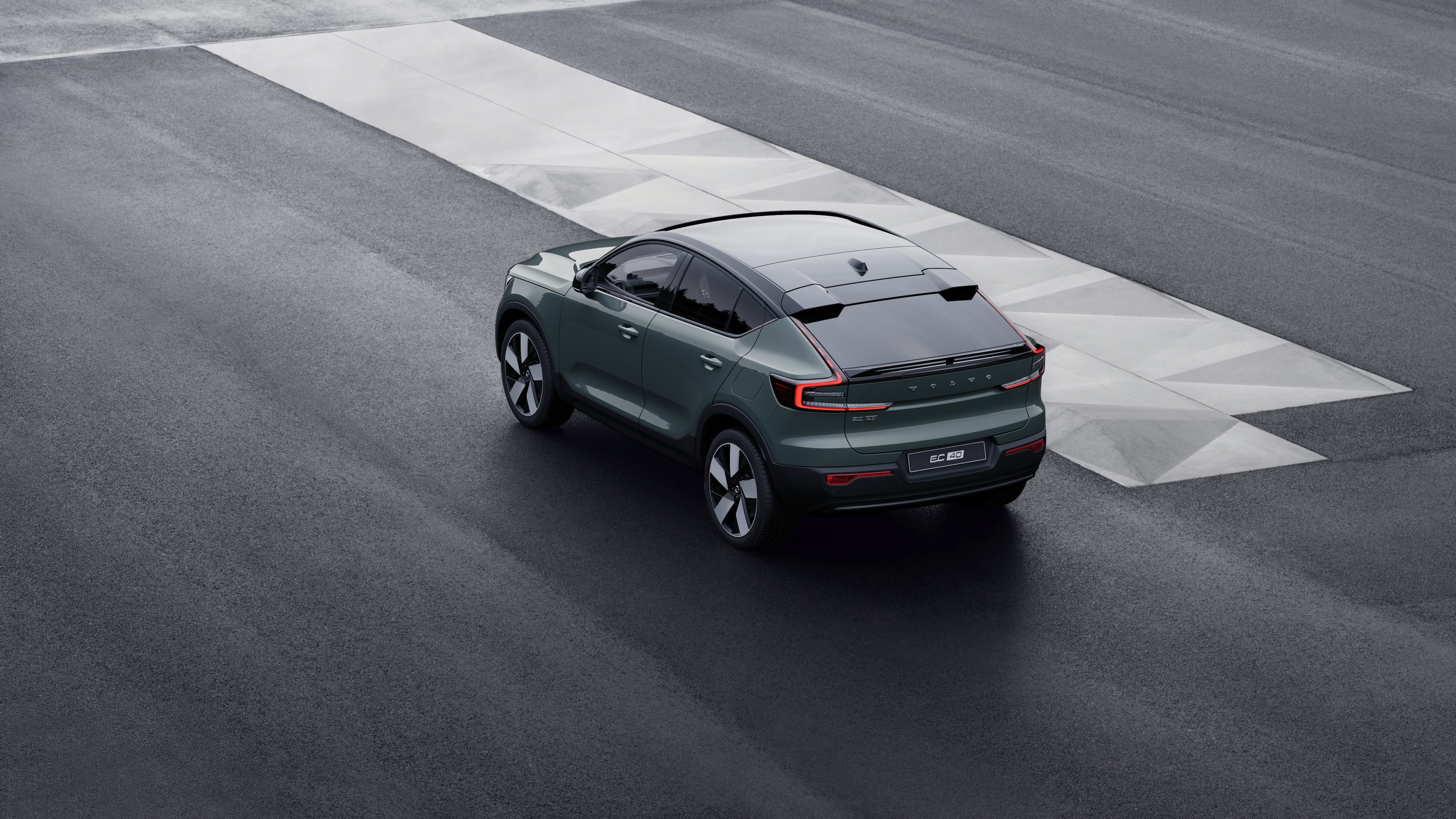 Volvo car in rear three-quarter view parked against a concrete wall on an urban street background.