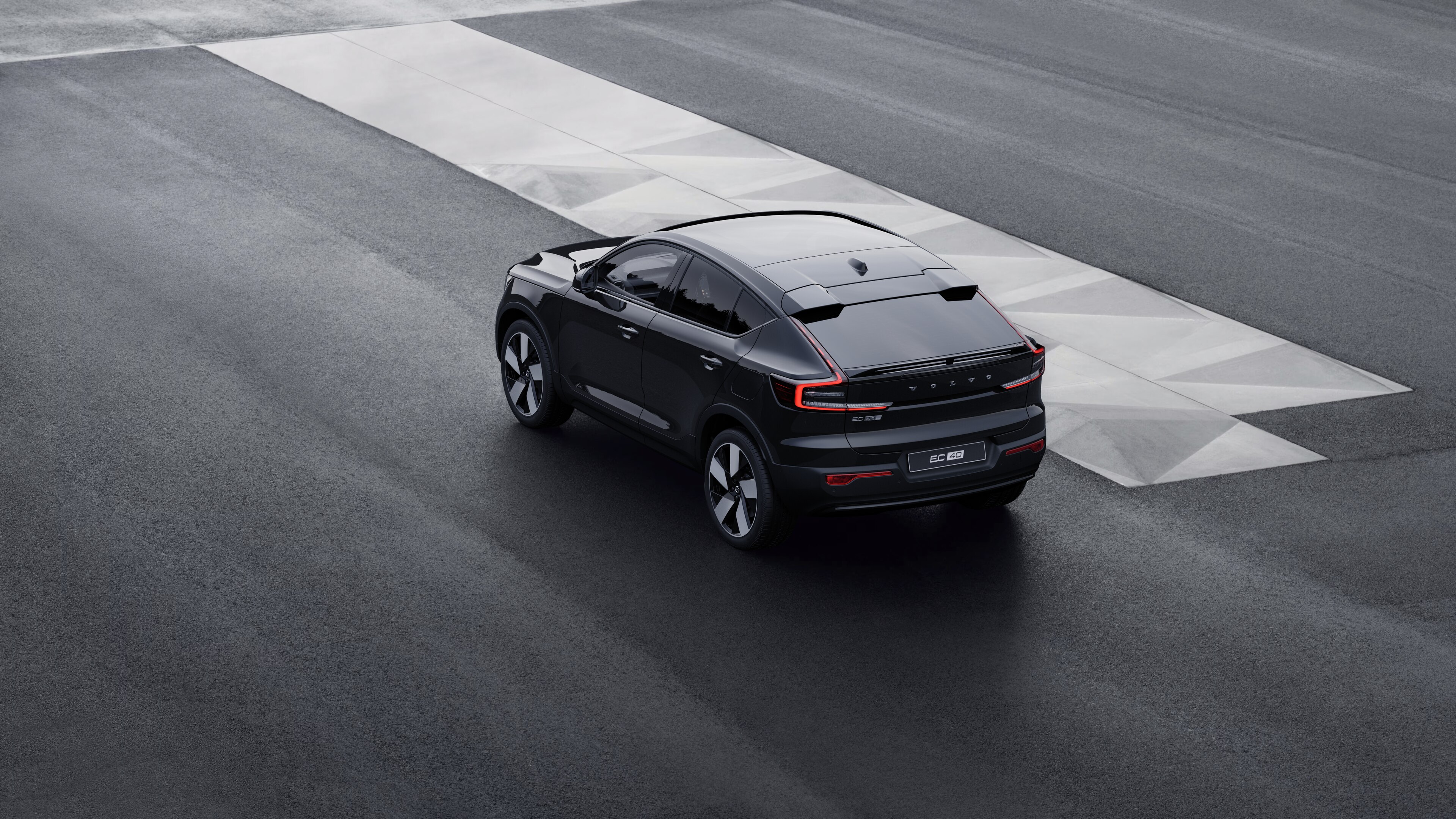 Volvo car in rear three-quarter view parked against a concrete wall on an urban street background.
