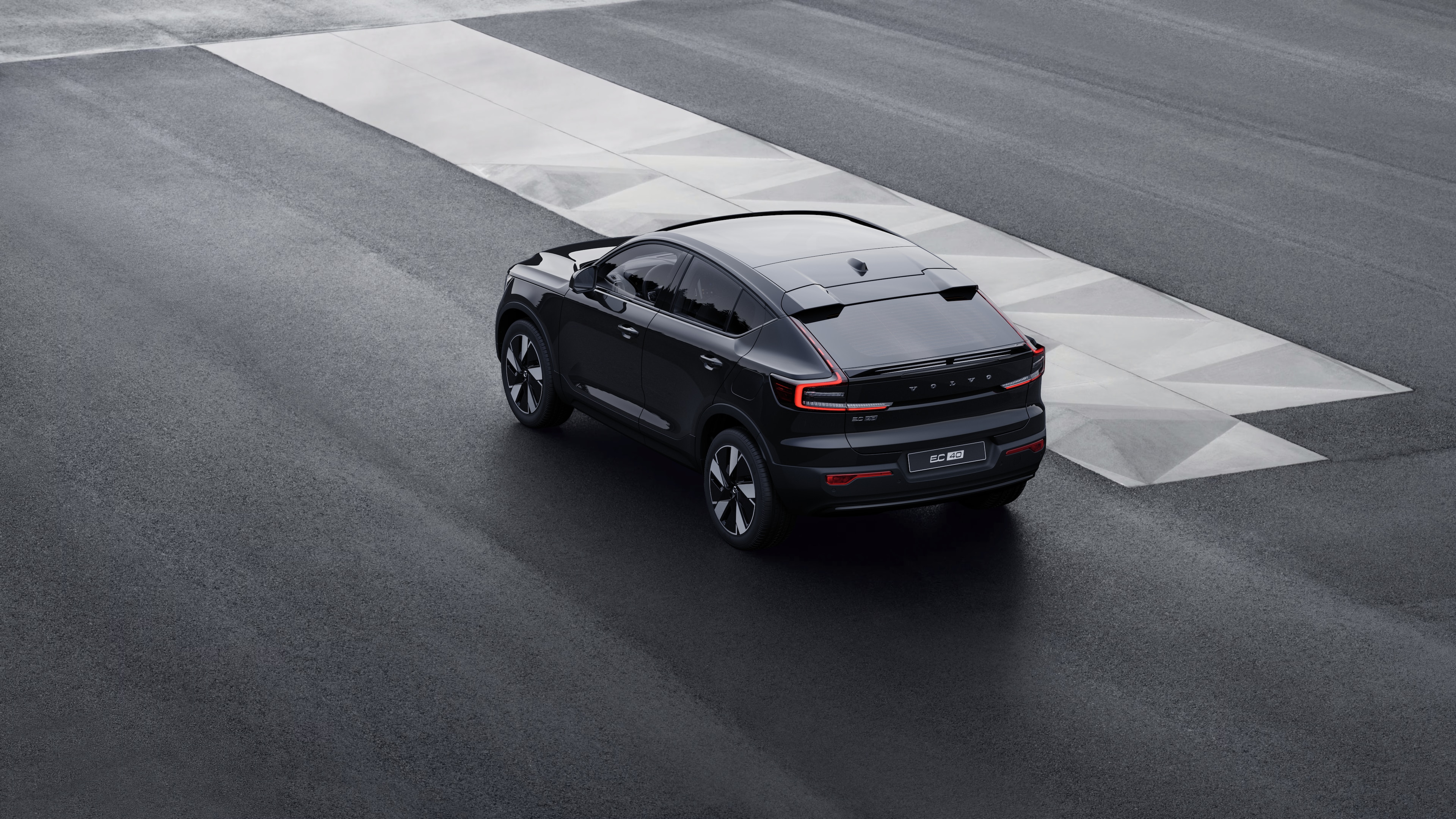 Volvo-auto in driekwart achteraanzicht geparkeerd tegen een betonnen muur op een stedelijke straatachtergrond.