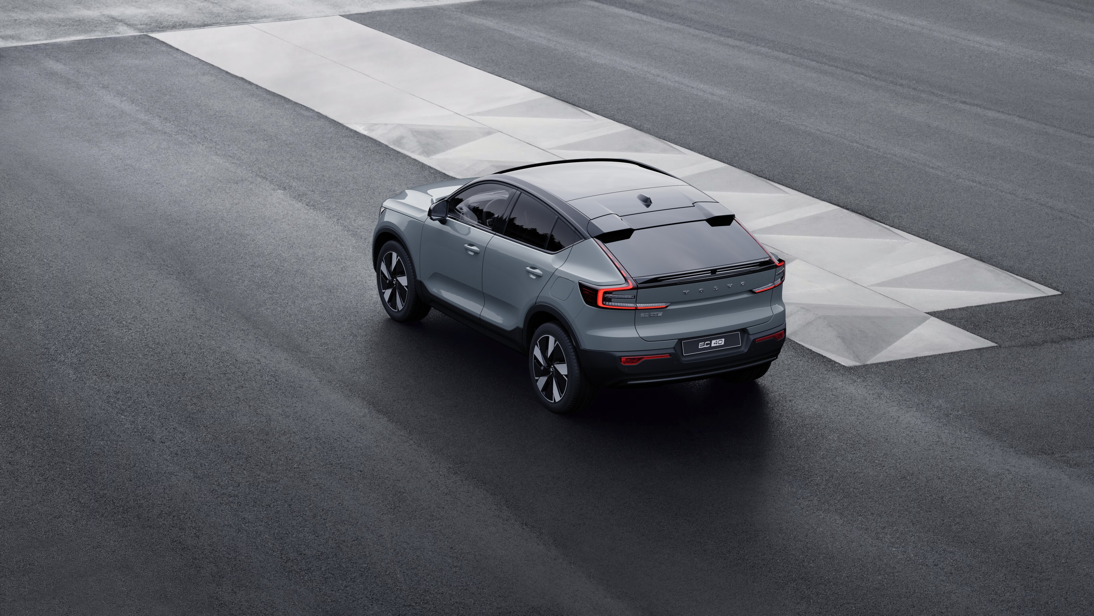 Driekwart achteraanzicht van een Volvo-auto geparkeerd tegen een betonnen muur op de achtergrond van een stedelijke straat.