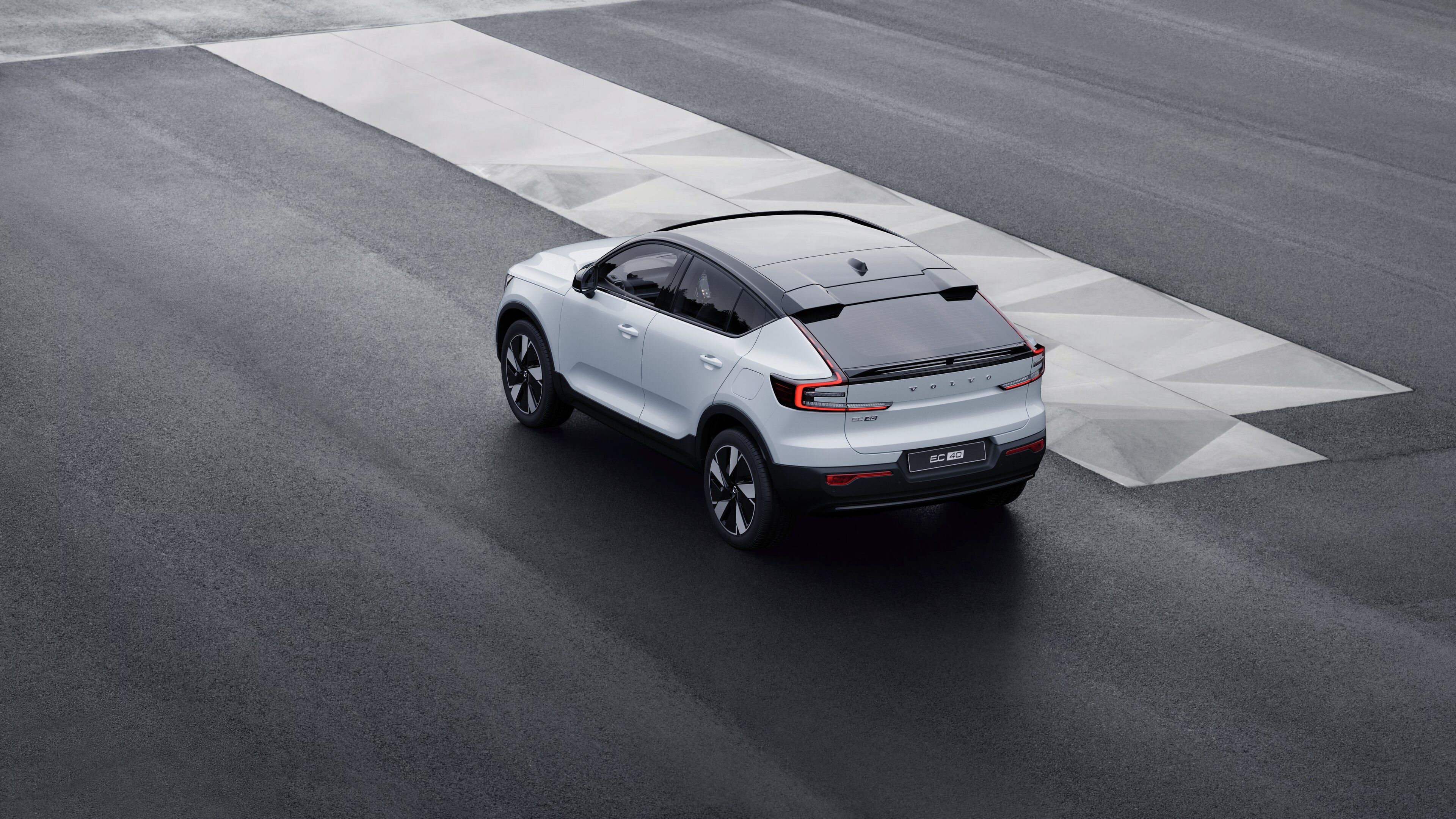 Volvo car in rear three-quarter view parked against a concrete wall on an urban street background.