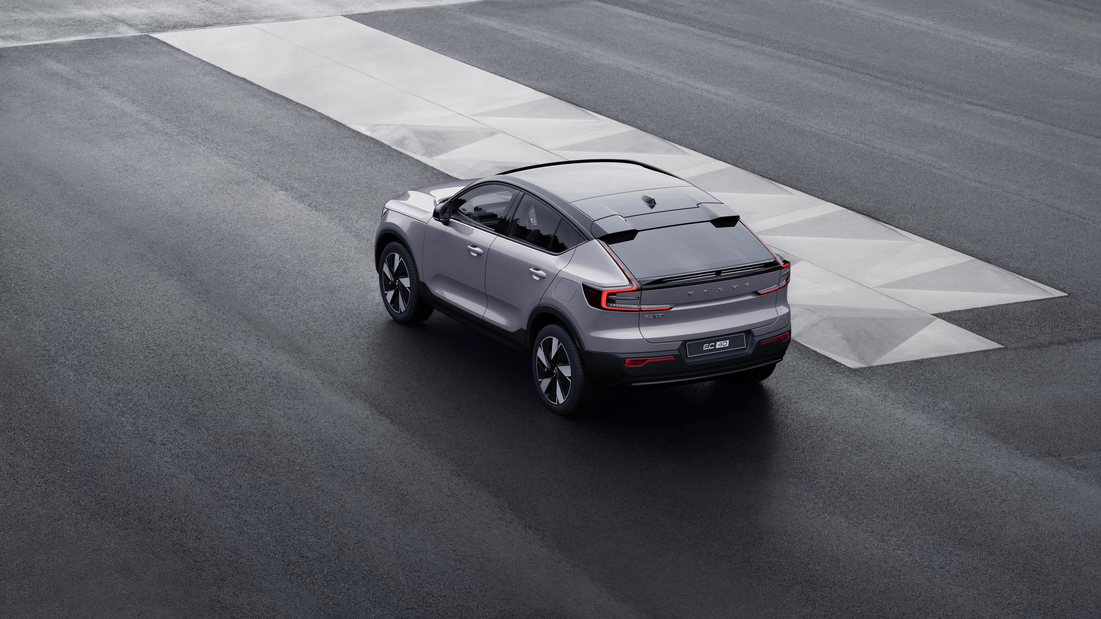 Volvo car in rear three-quarter view parked against a concrete wall on an urban street background.