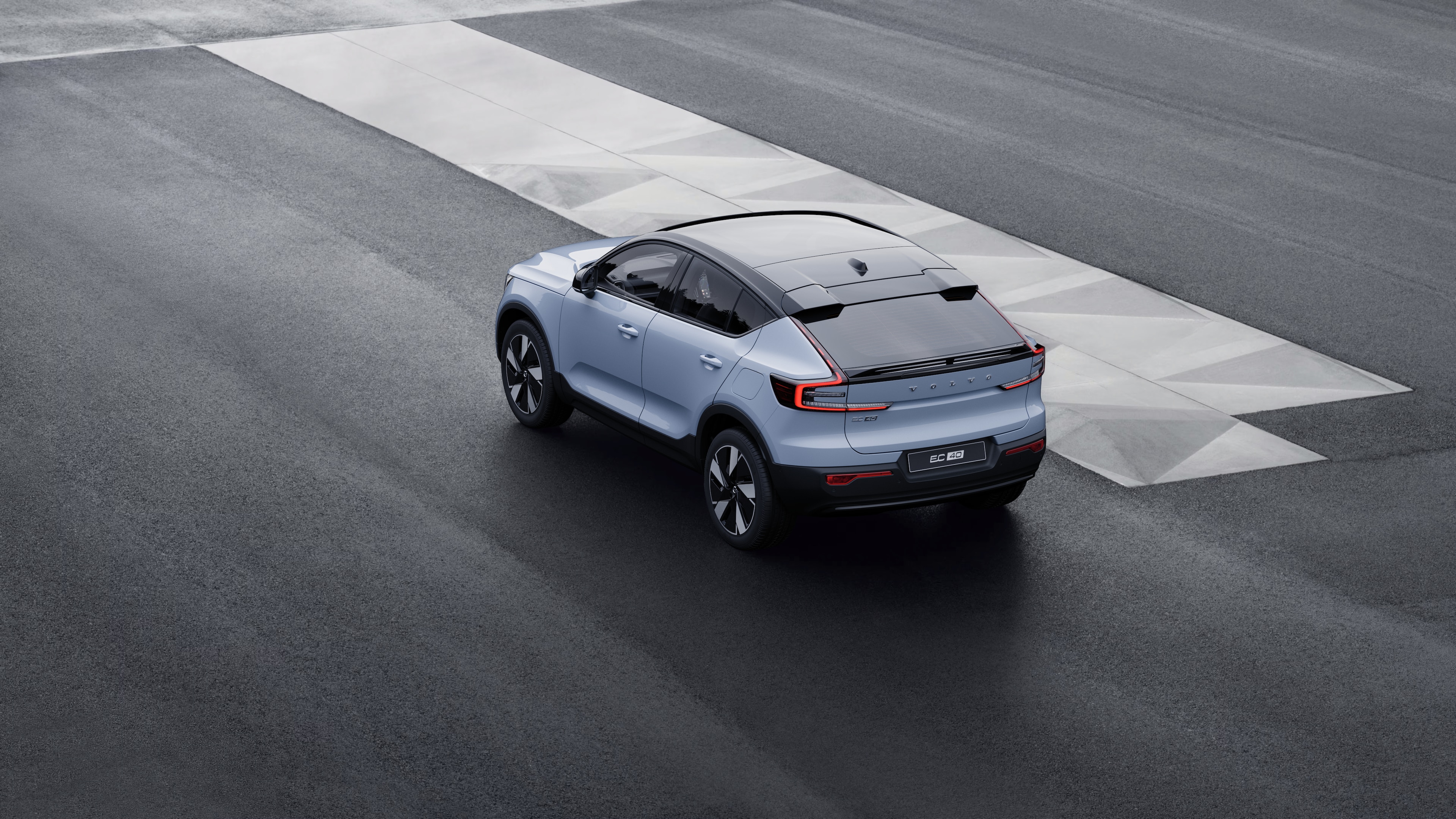 Volvo car in rear three-quarter view parked against a concrete wall on an urban street background.