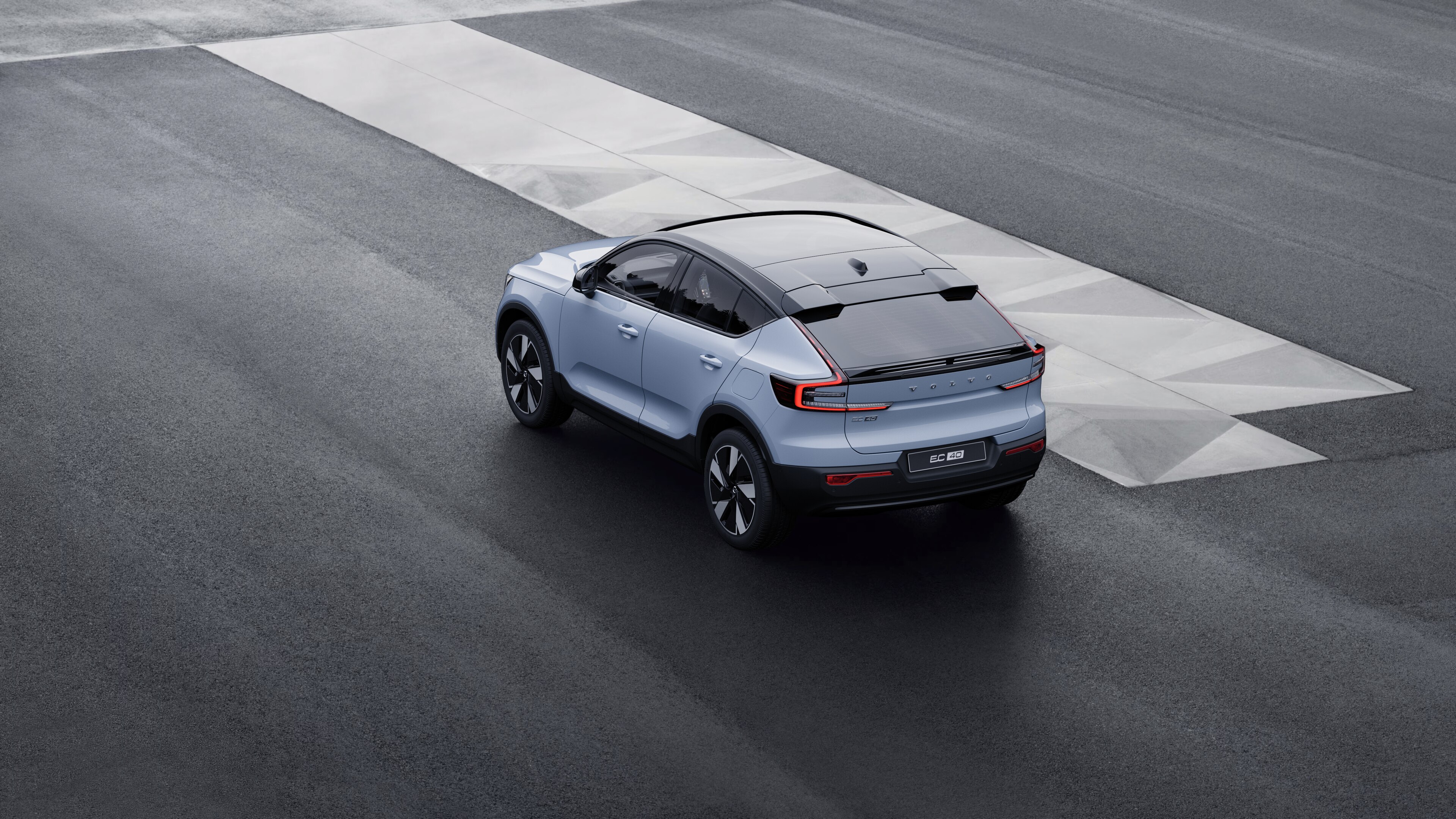 Volvo car in rear three-quarter view parked against a concrete wall on an urban street background.