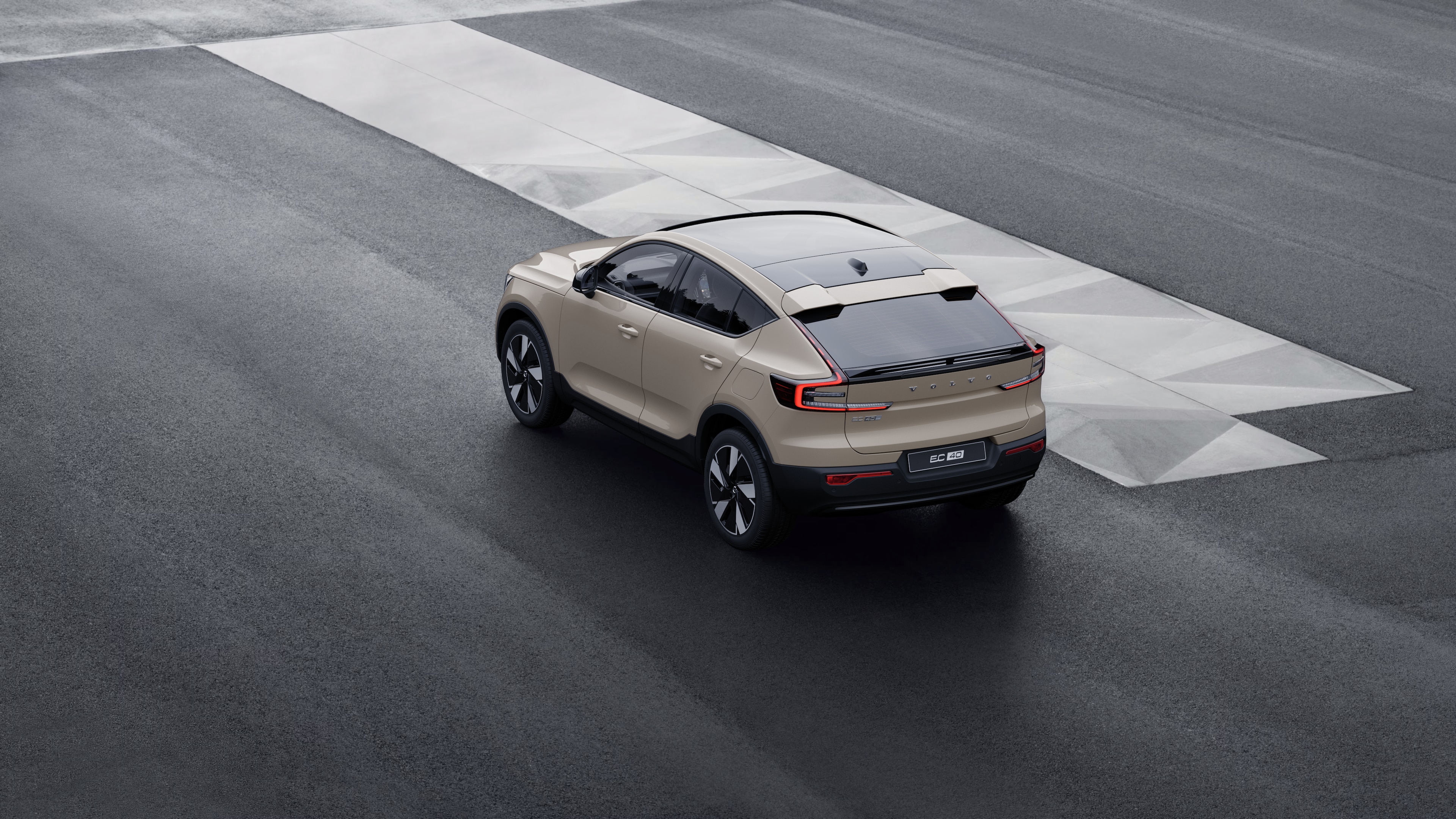 Volvo car in rear three-quarter view parked against a concrete wall on an urban street background.